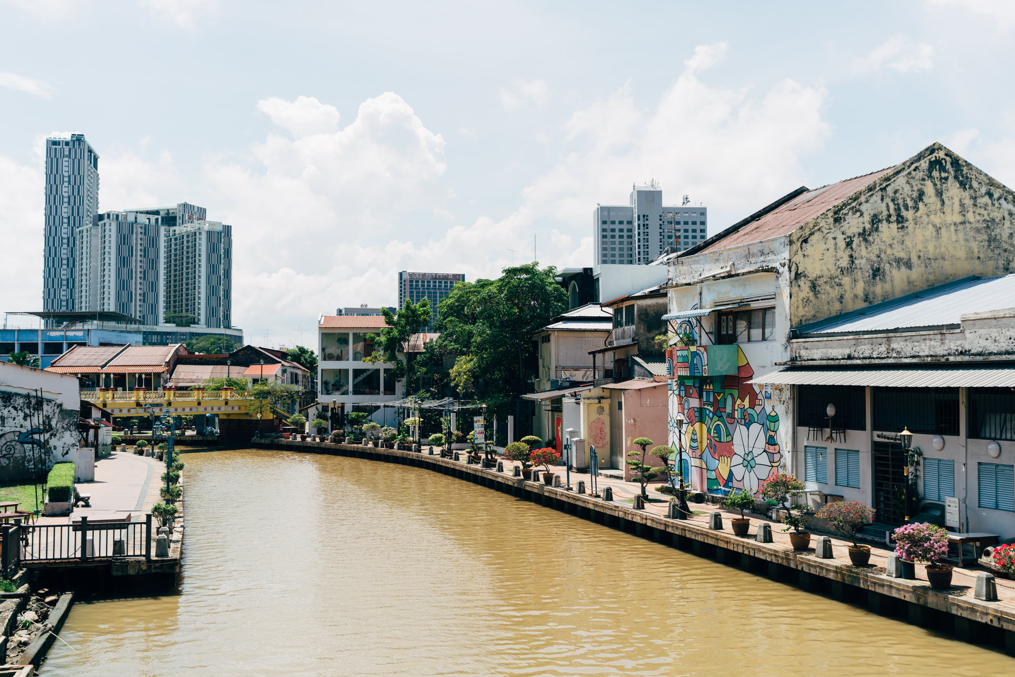 Malacca riverfront with colorful buildings and modern high-rises in the background.