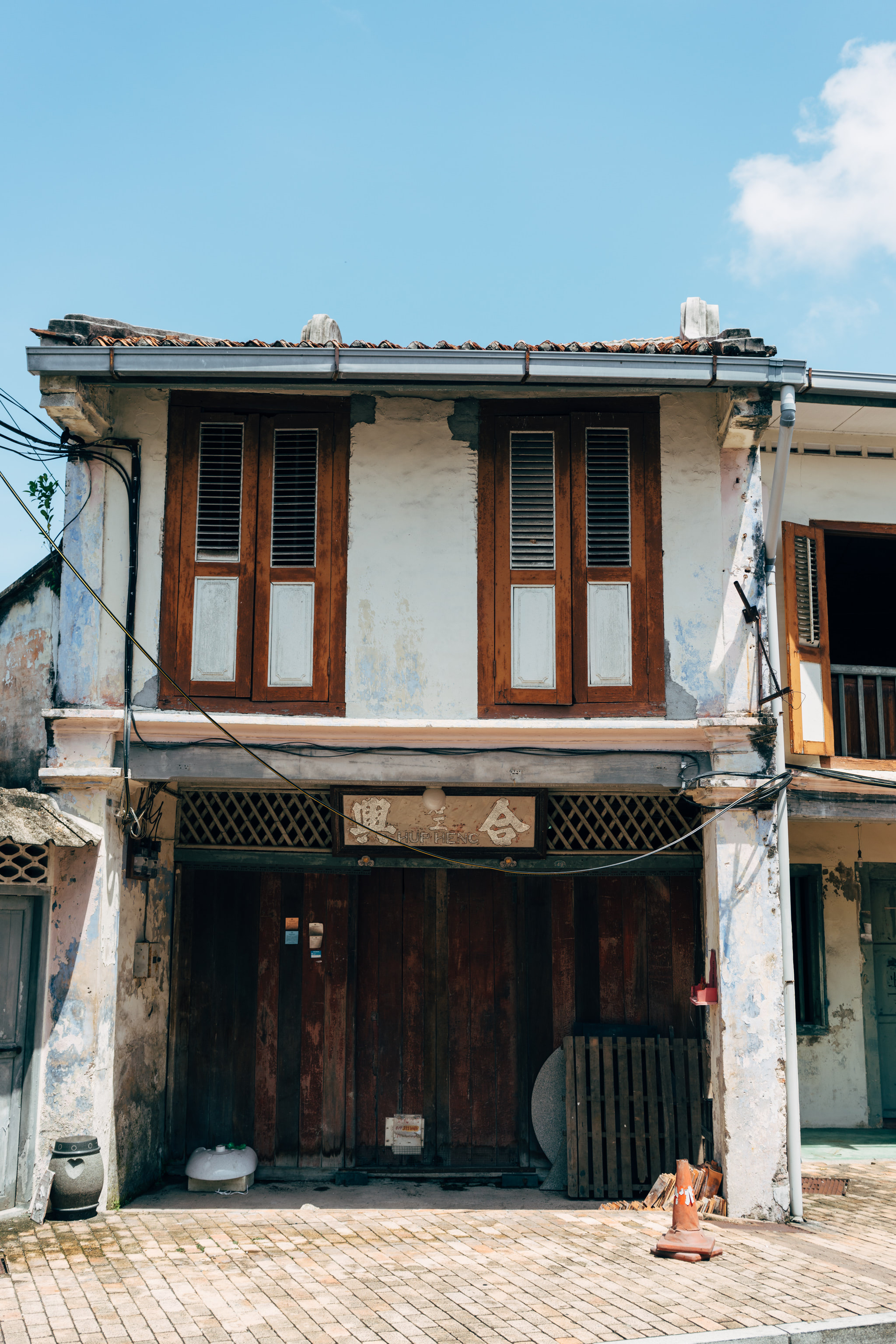 Old weathered building in Malacca, Malaysia, with brown wooden doors and windows.