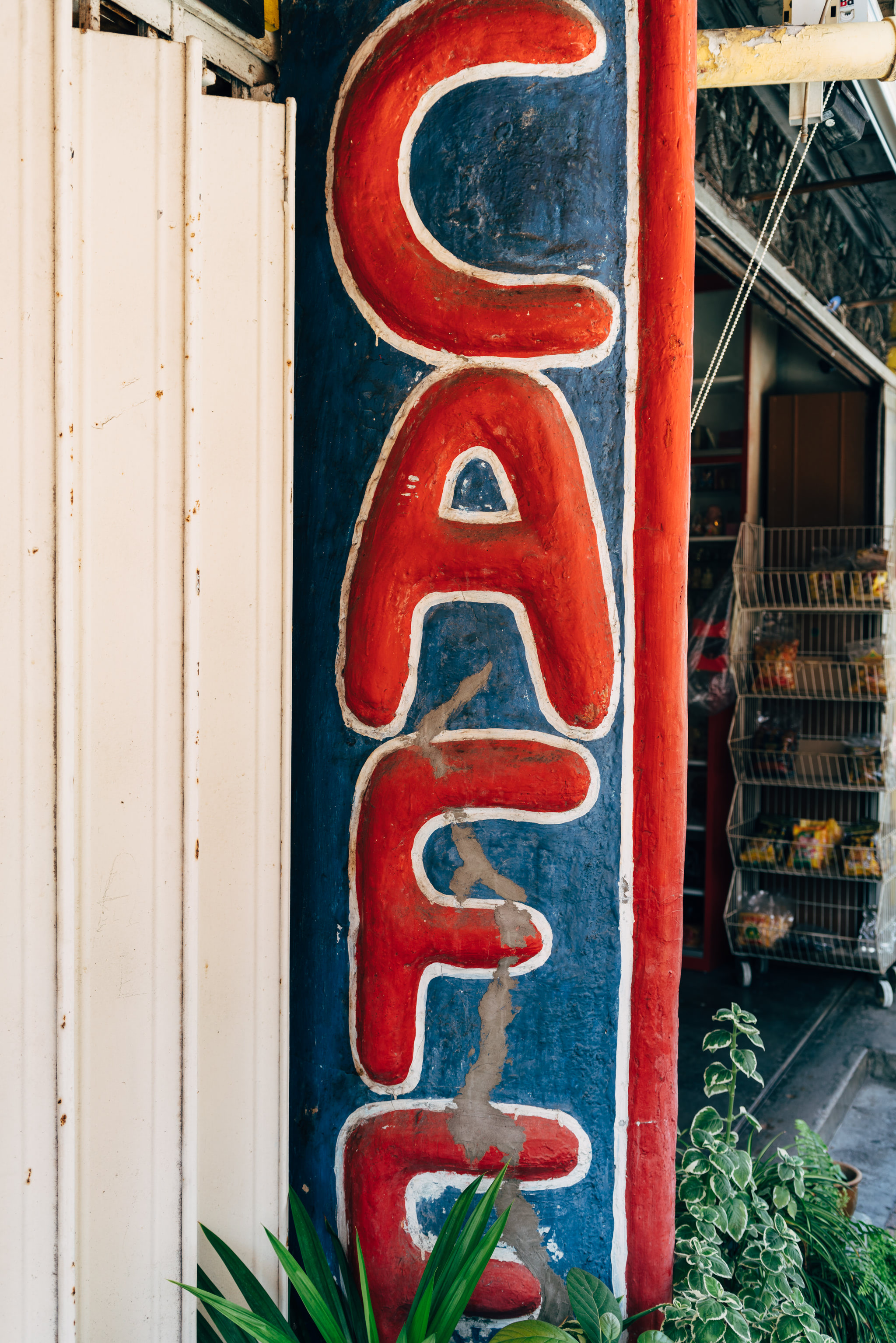 Hand-painted red 'CAFE' sign on a blue wall.