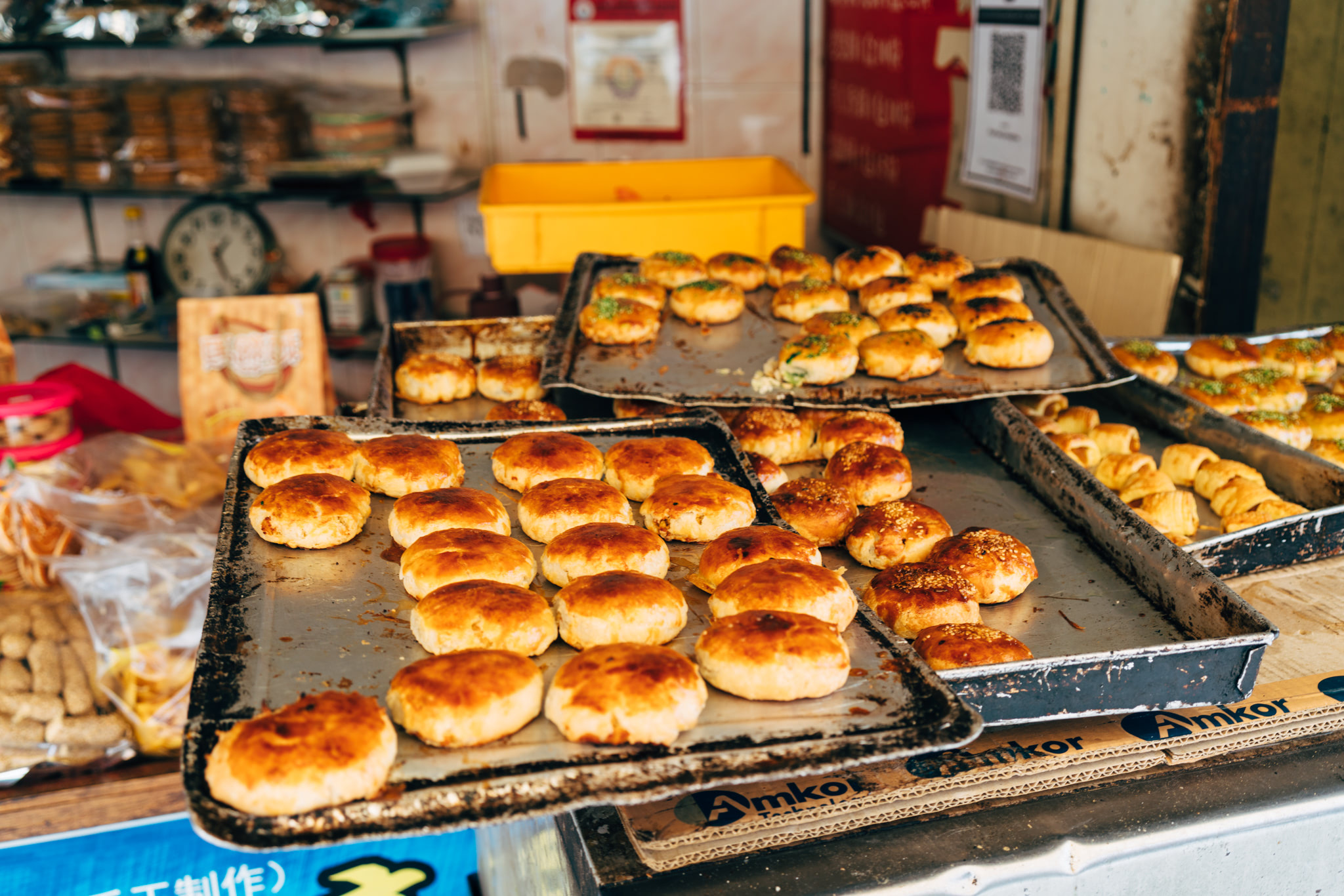 Several baking sheets filled with golden-brown Malaysian bread buns.