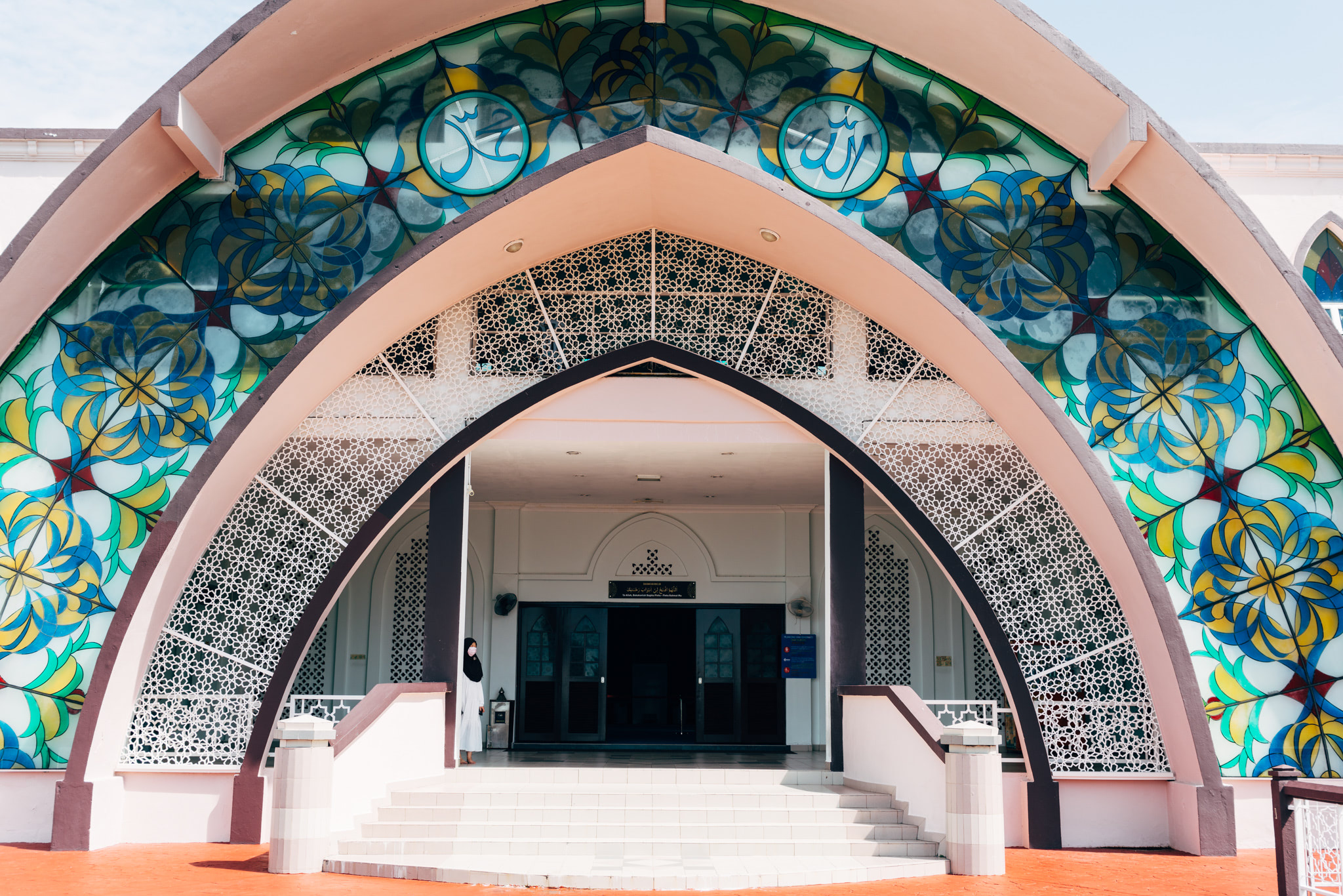 Entrance to the Straits Mosque in Malacca, Malaysia, featuring stained-glass windows and intricate latticework.