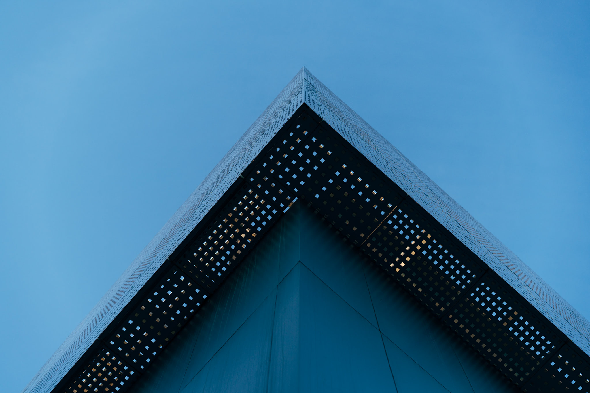 Low-angle view of a building corner with a patterned metal overhang.