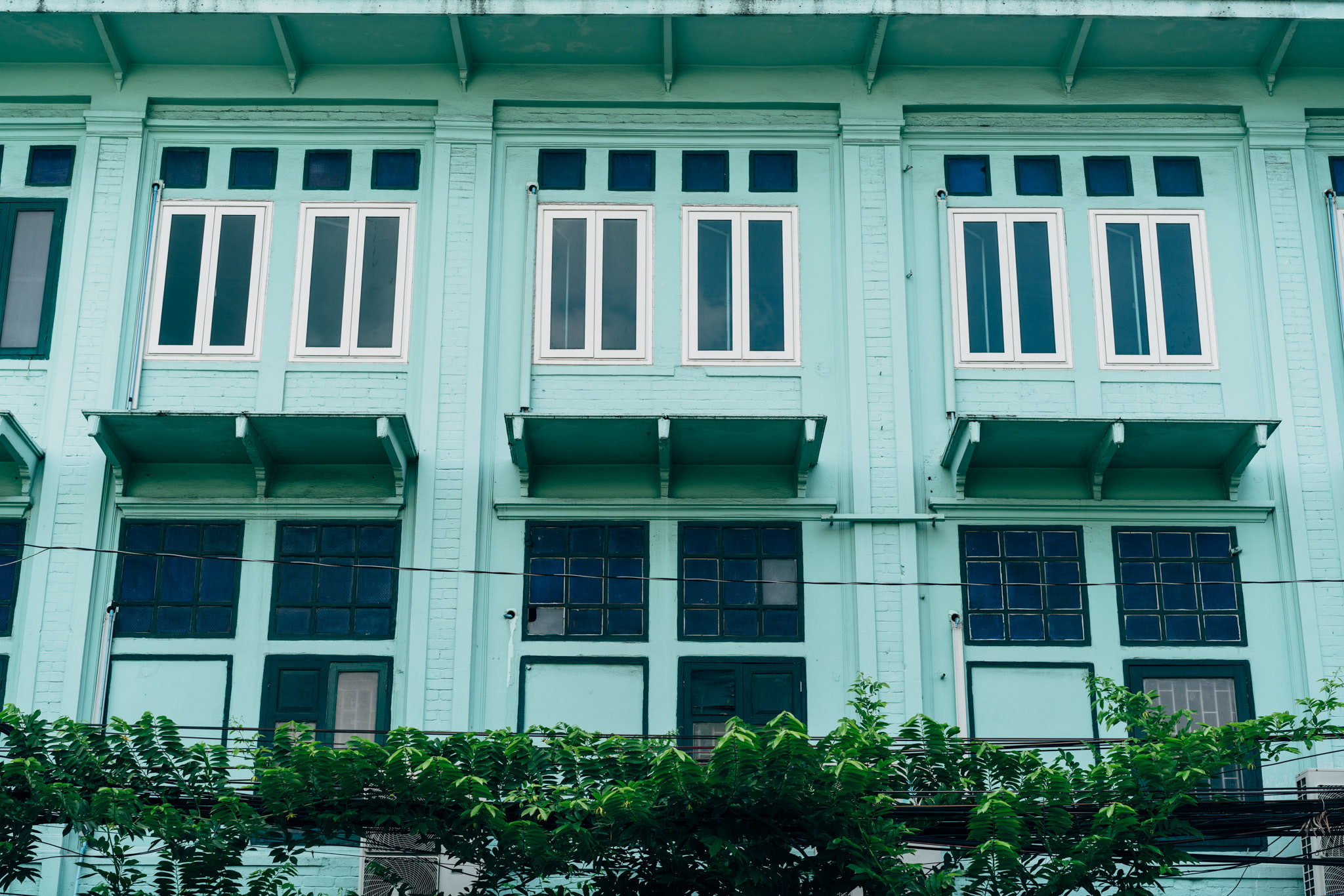 Teal building facade with multiple windows and small balconies.