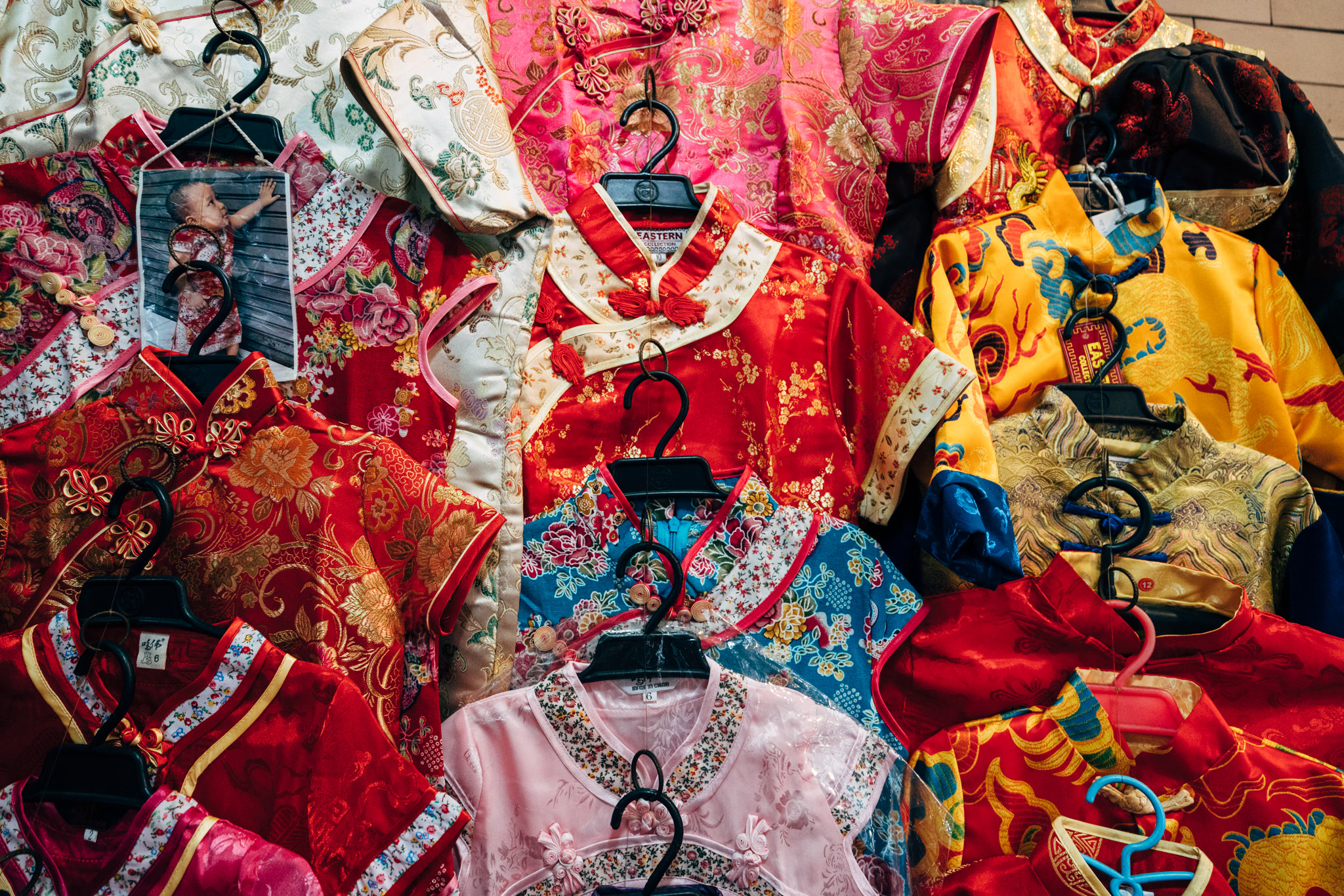Many colorful traditional Chinese shirts on hangers.