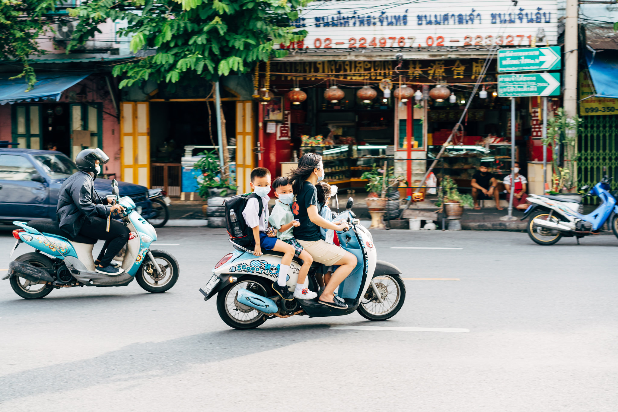 Family on motorbike in Asia, children wearing masks.