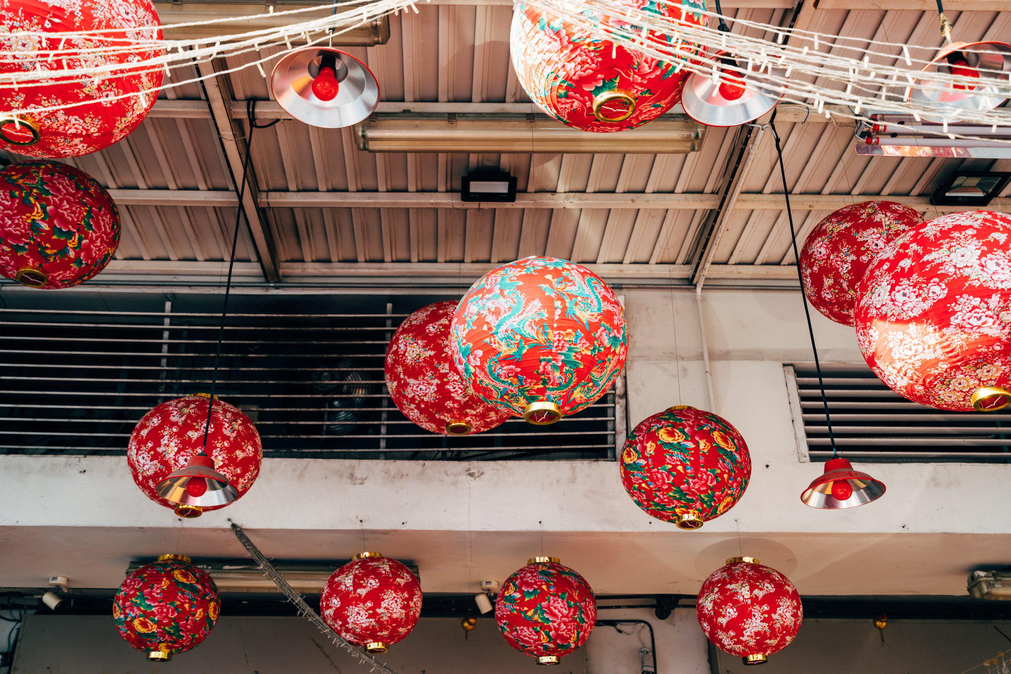 Many red and gold Chinese lanterns hanging from a ceiling.