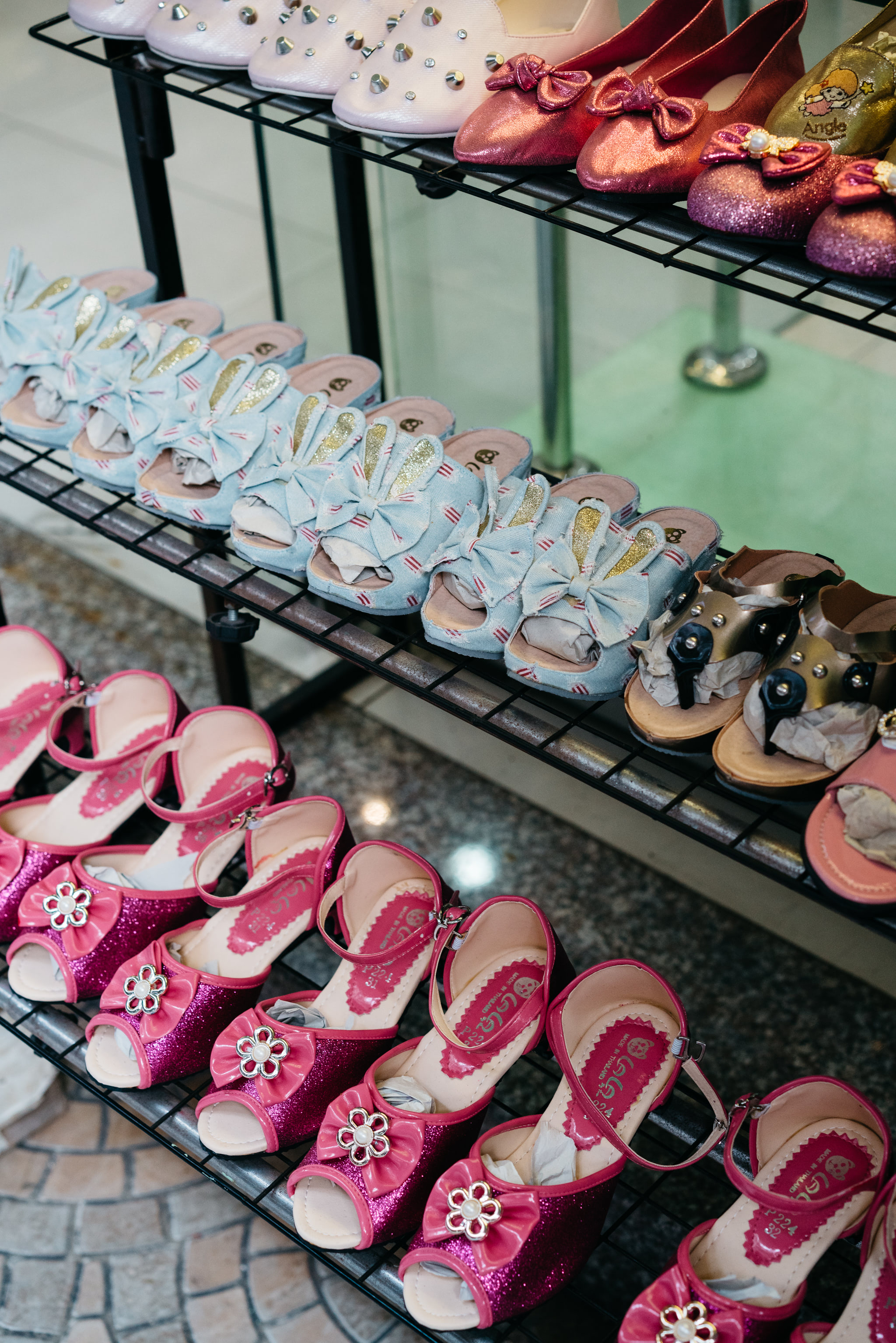 Multiple rows of children's shoes on a display rack.