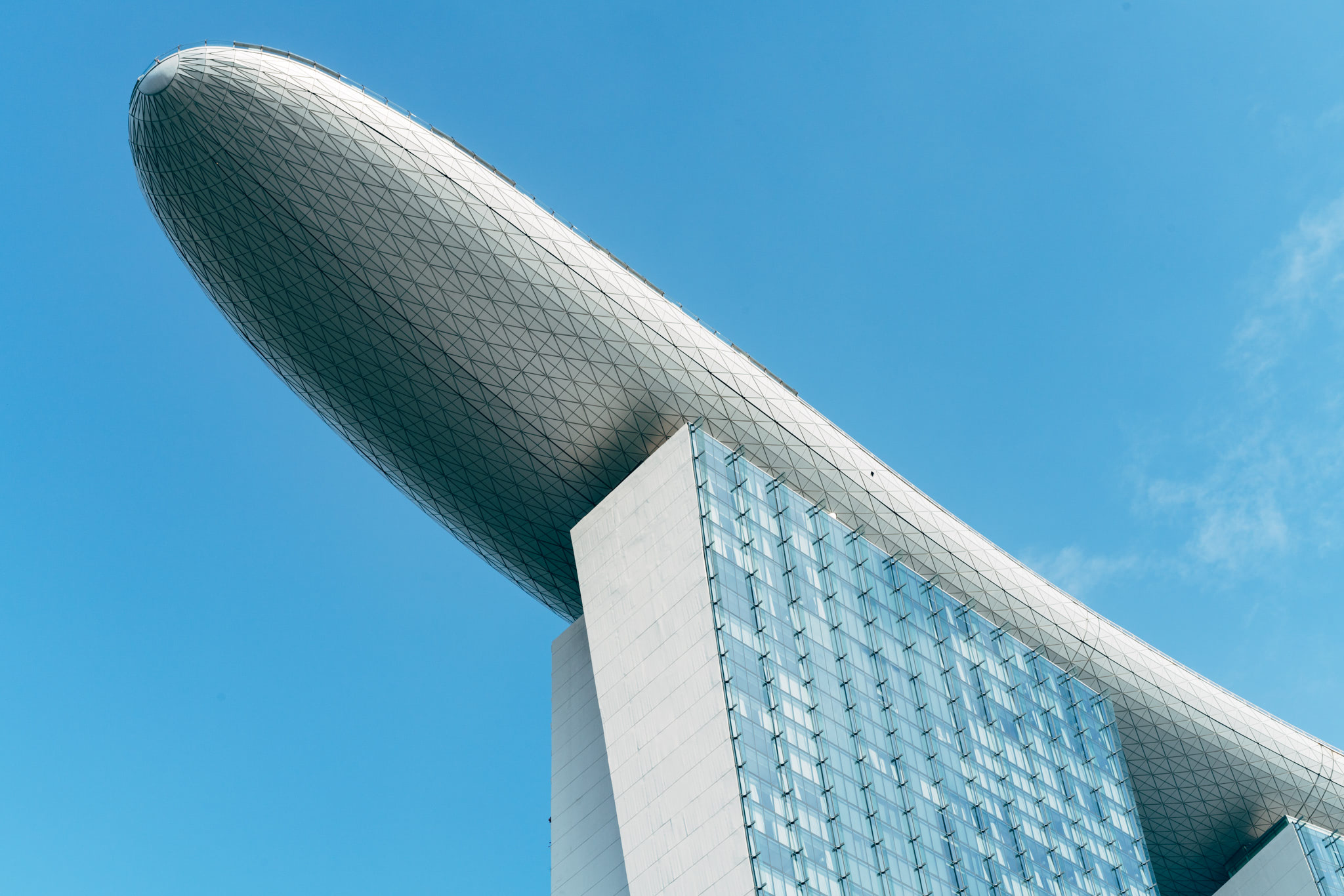 Low-angle view of the Marina Bay Sands hotel's iconic boat-shaped rooftop against a clear blue sky.