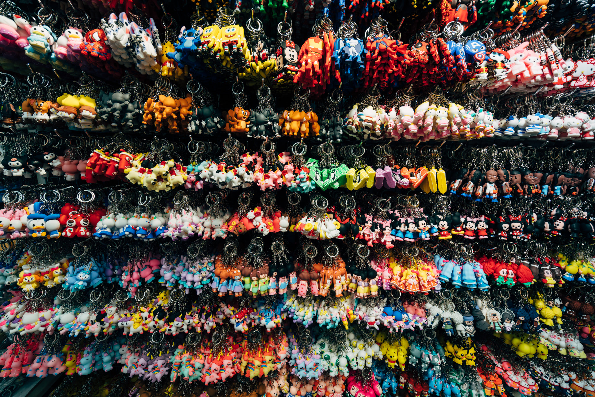 Many colorful cartoon character keychains displayed in rows.