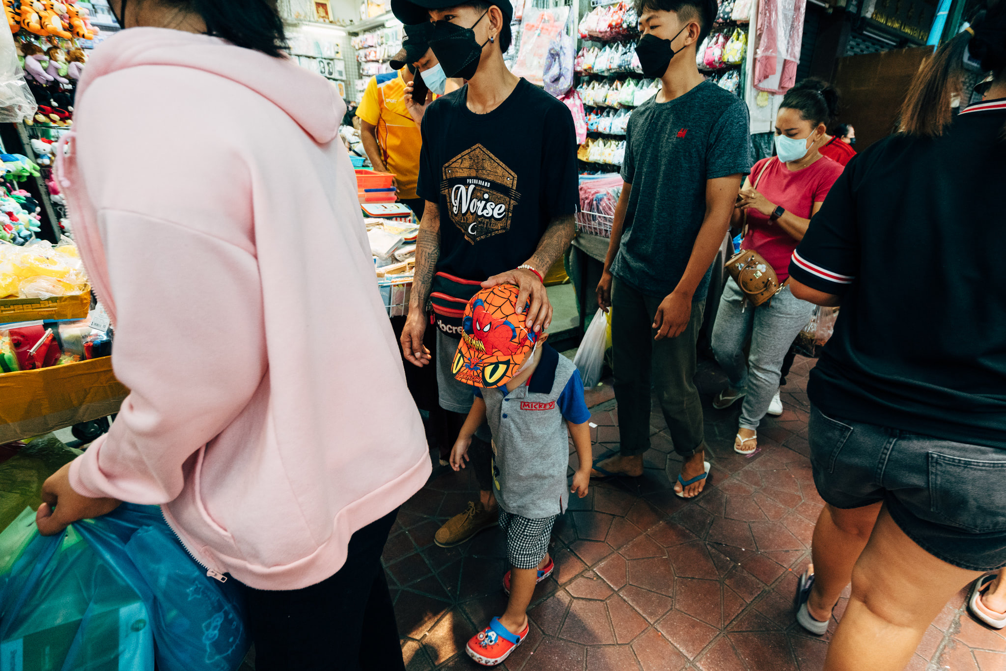 A crowded Thai shopping district with people wearing face masks.