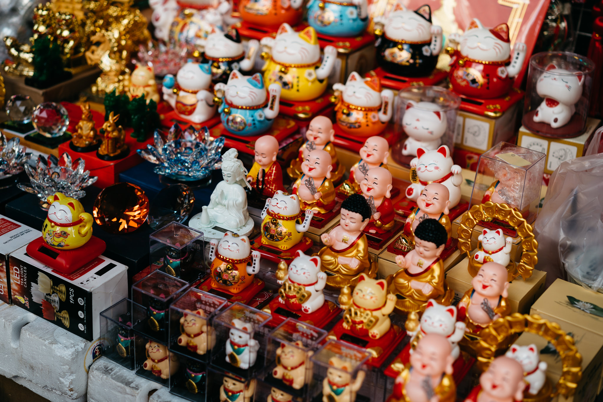 Many Maneki-neko and Buddha figurines displayed for sale in a Thai shopping district.