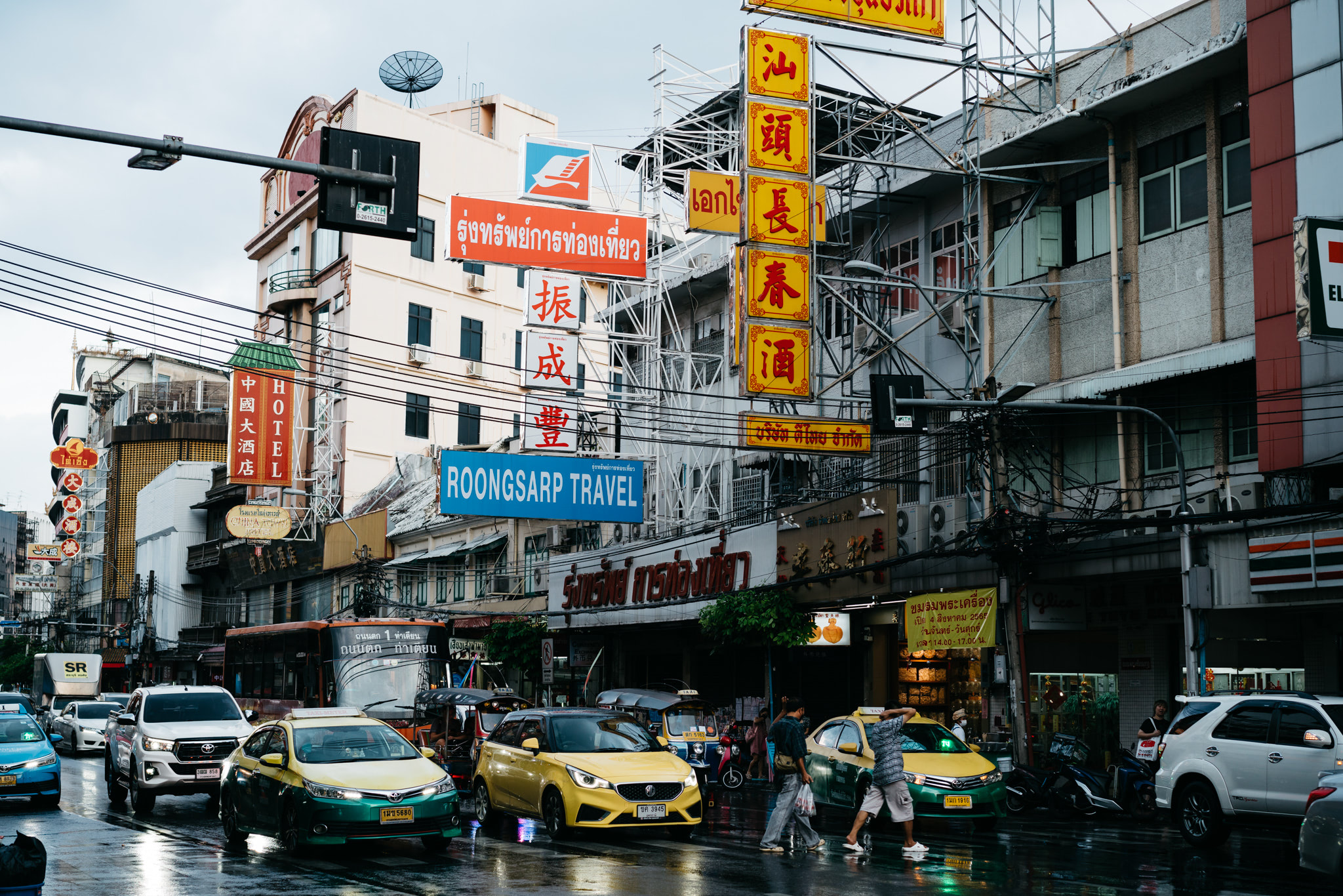 Busy Thai street scene with shops, traffic, and numerous signs in Thai and Chinese.