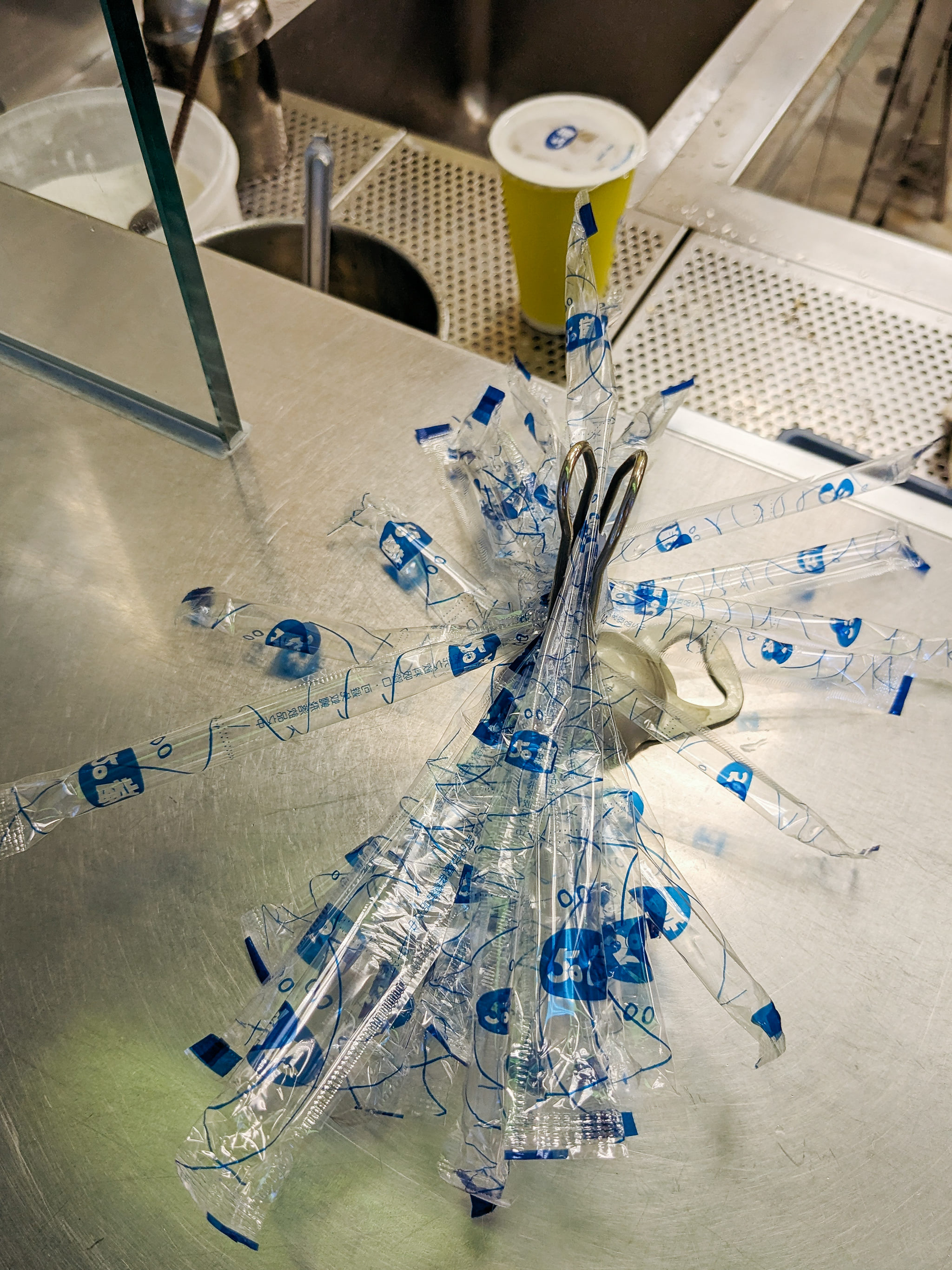 Bundle of plastic straws in individual wrappers on a counter.