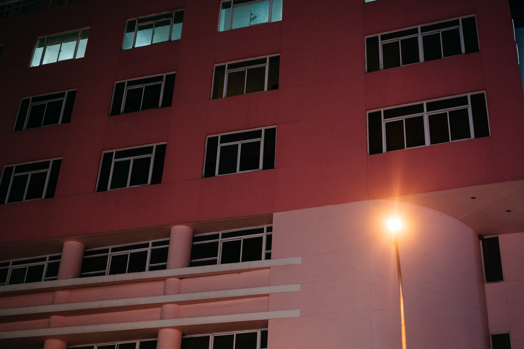 Night view of a multi-story building with dark windows and a single lit streetlamp.