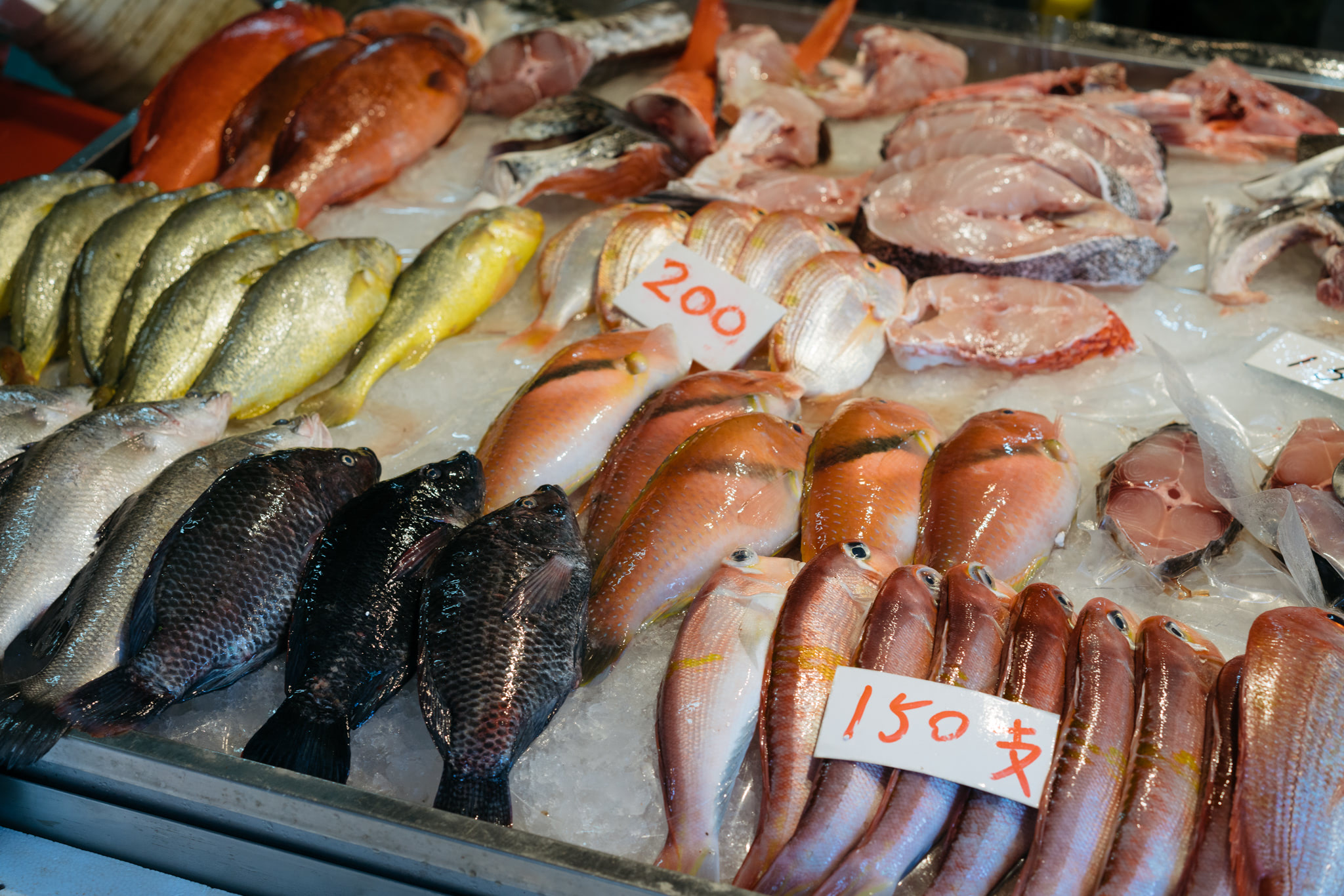 Taipei fish market with various fish on ice, some with price tags.