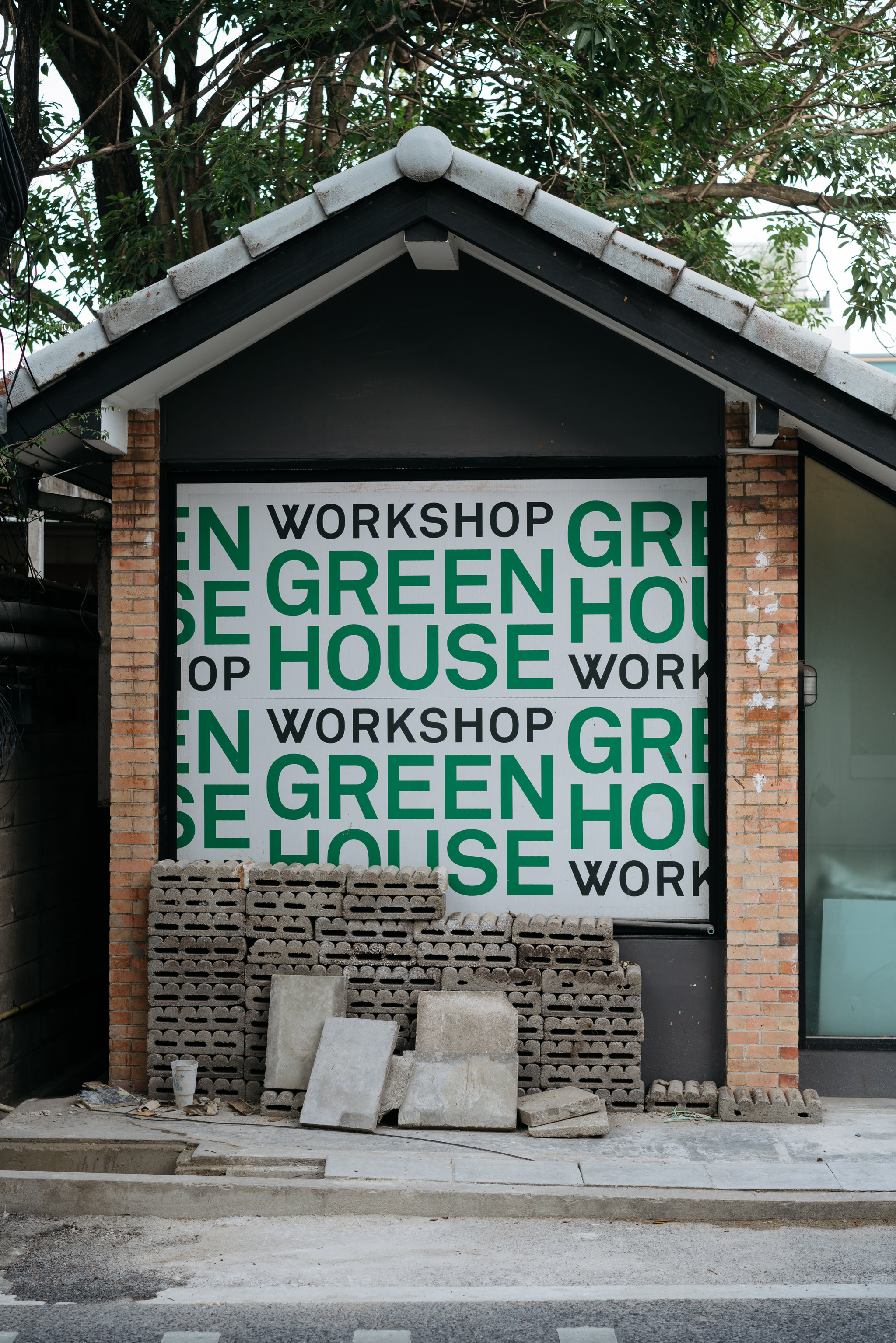 Brick building with a sign that says 'Workshop Greenhouse' in green and black text.
