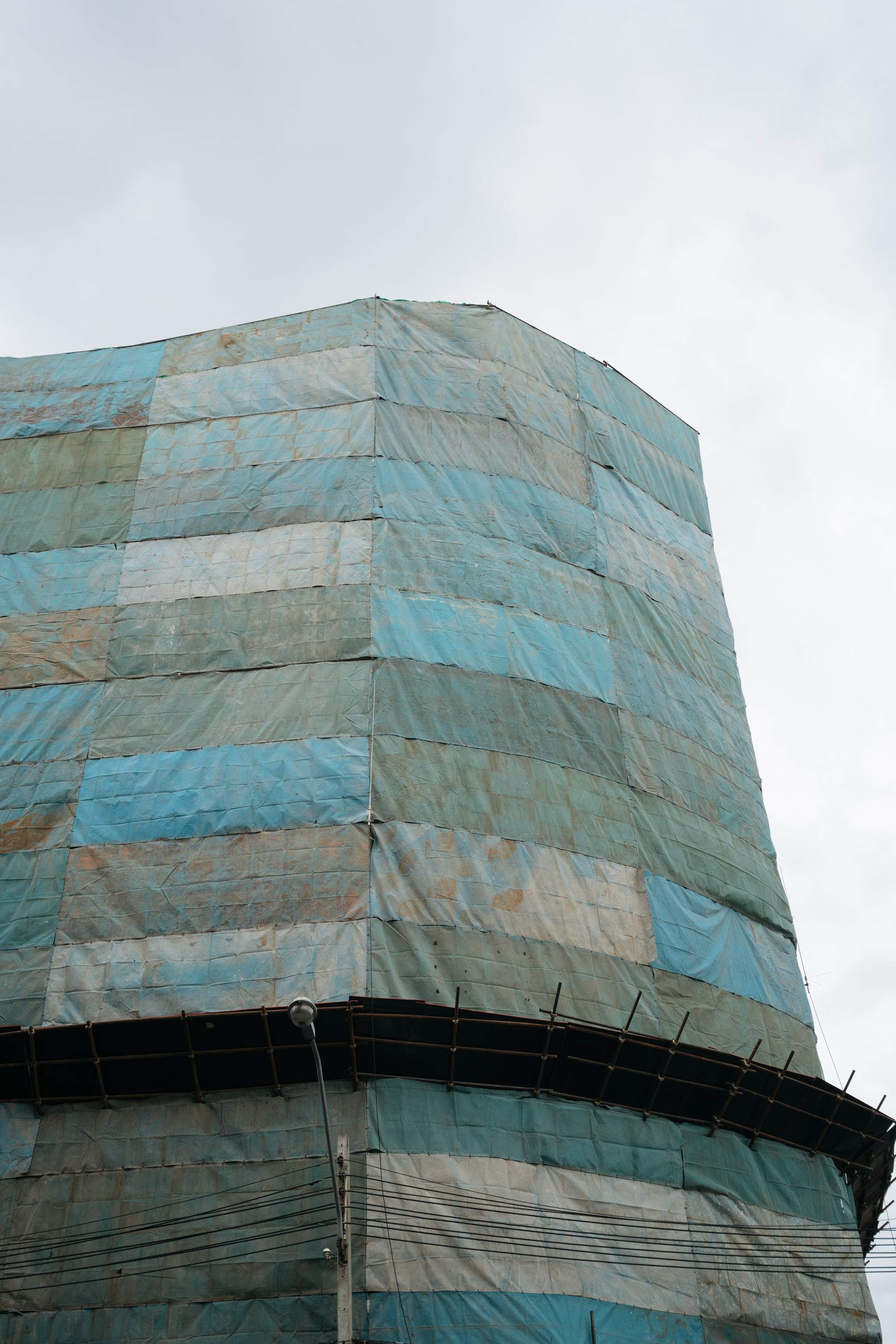 Construction site building covered in blue and grey tarp.