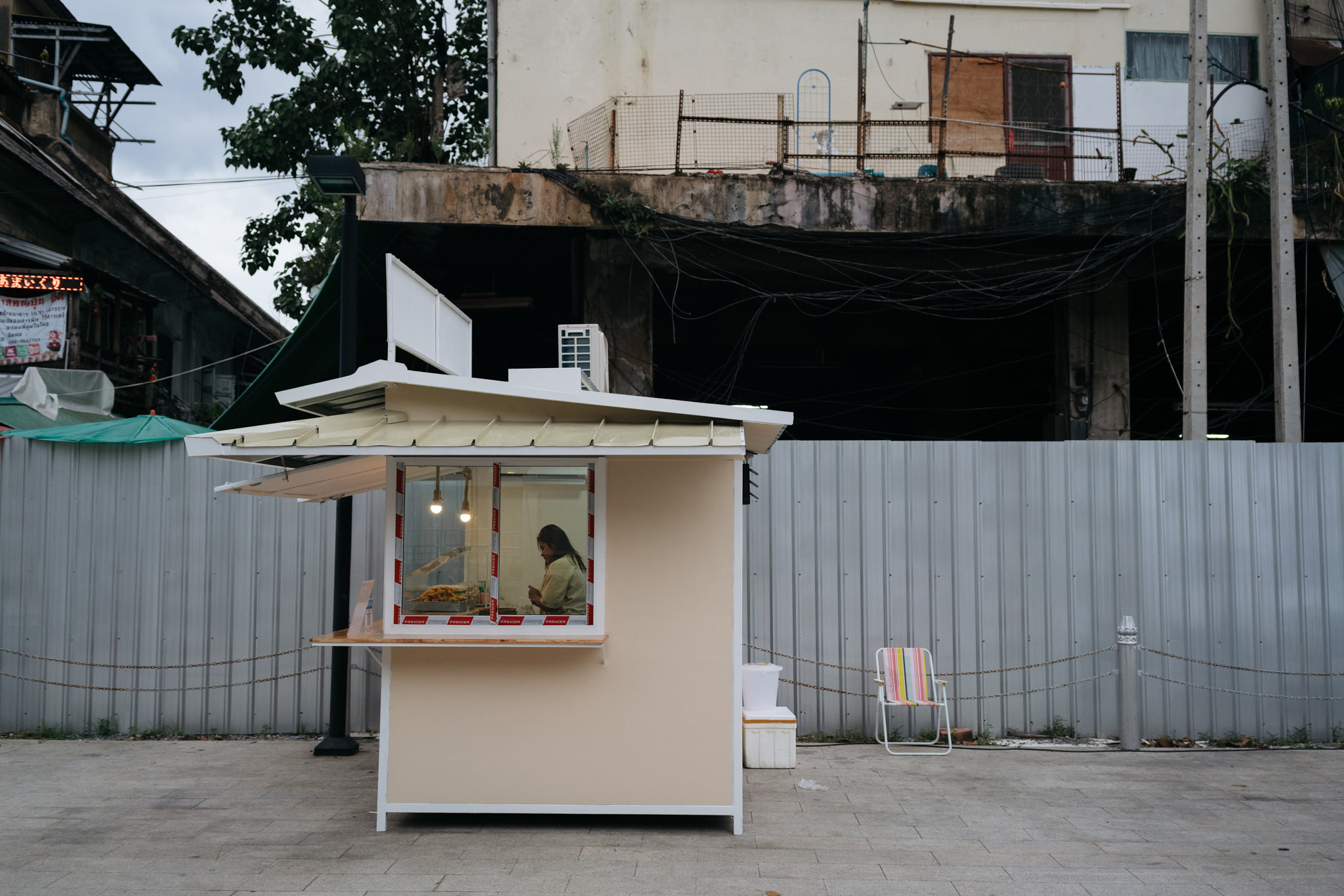 Woman working in a small, light beige food stall.