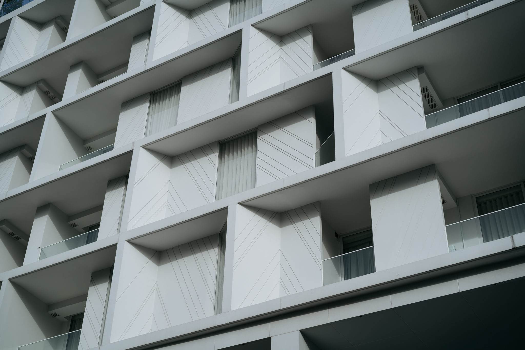 Low-angle view of a modern building's exterior with a geometric design and balconies.