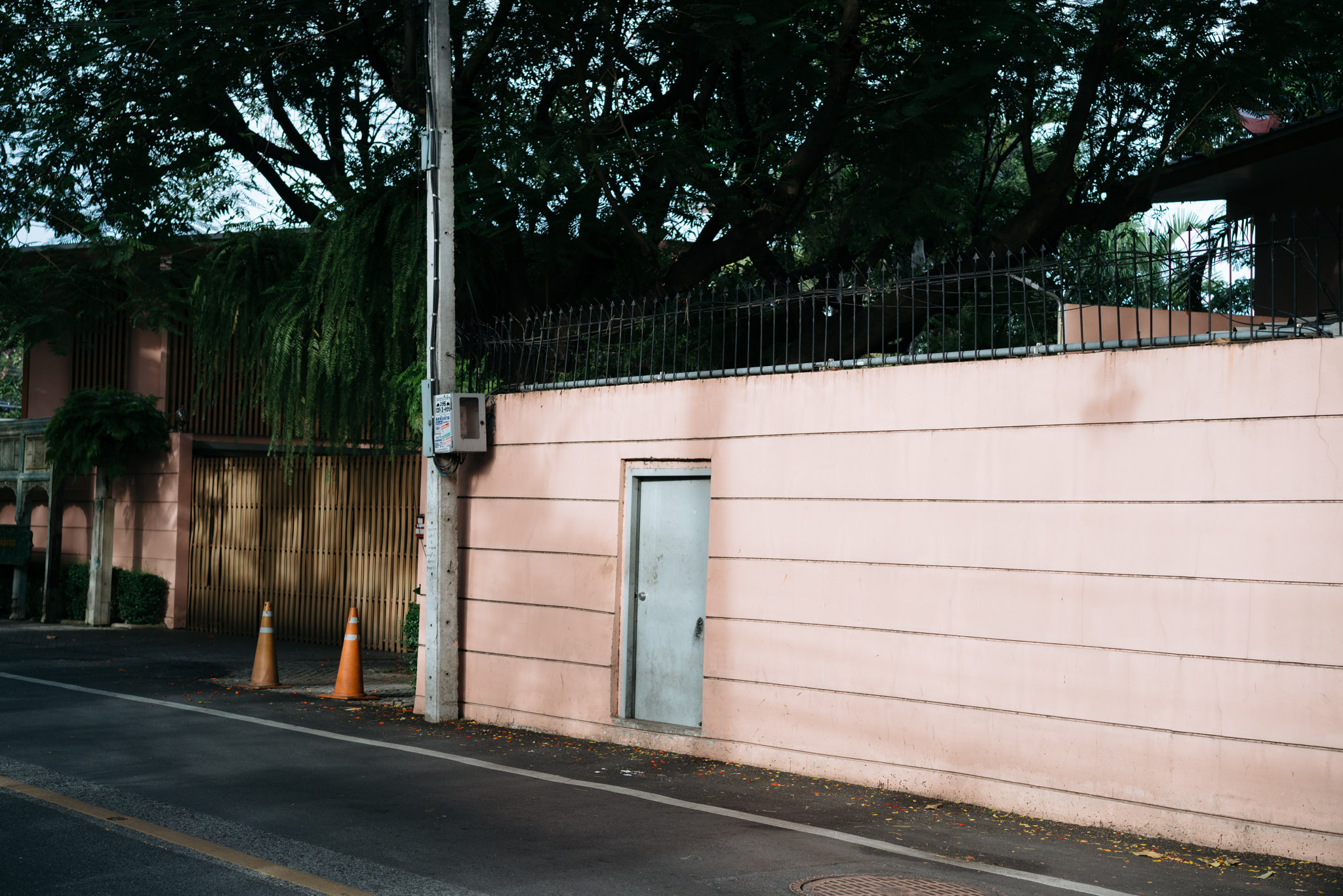 Pink wall with a metal door, security fence, and utility pole.