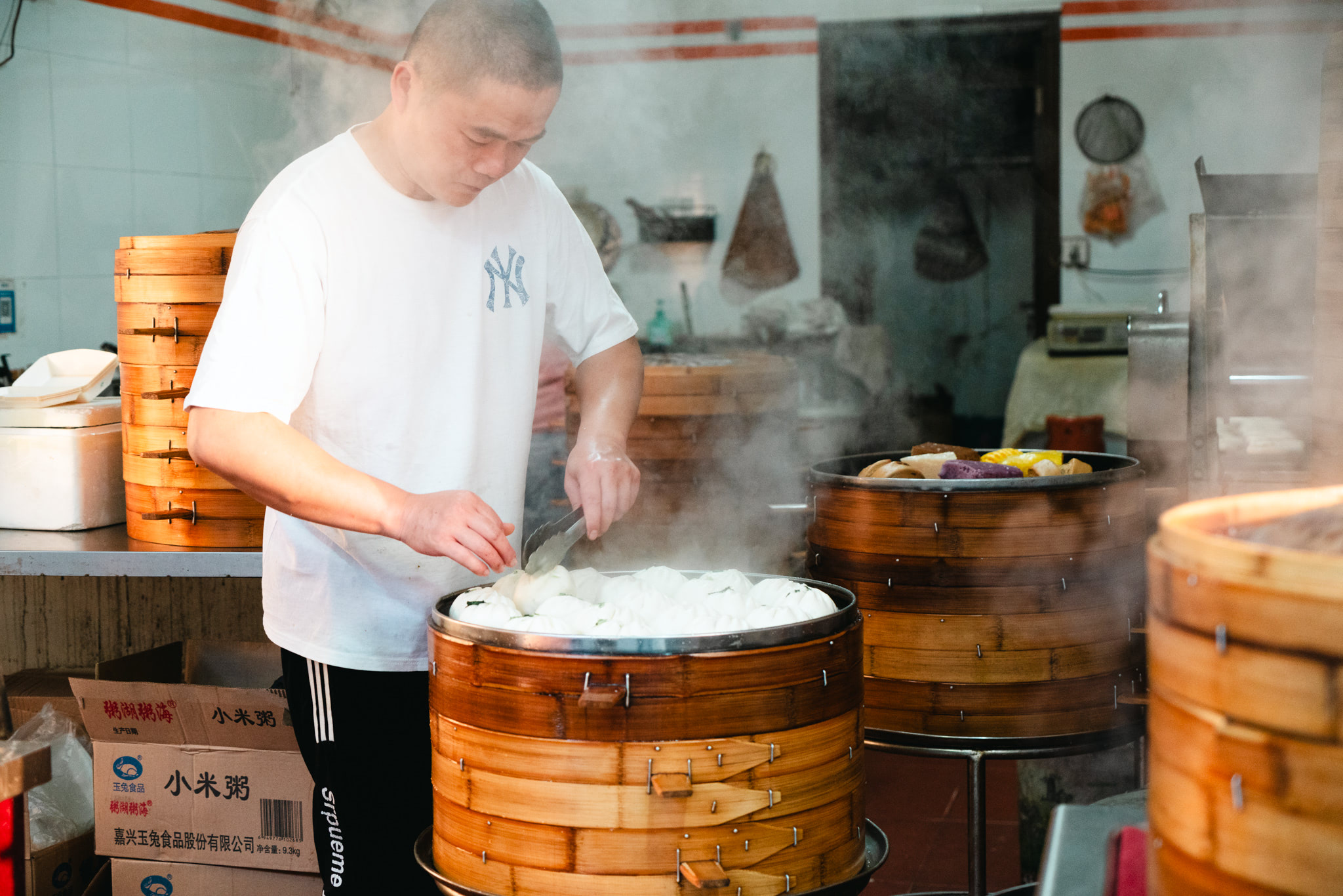Street vendor steaming dumplings in bamboo steamers.