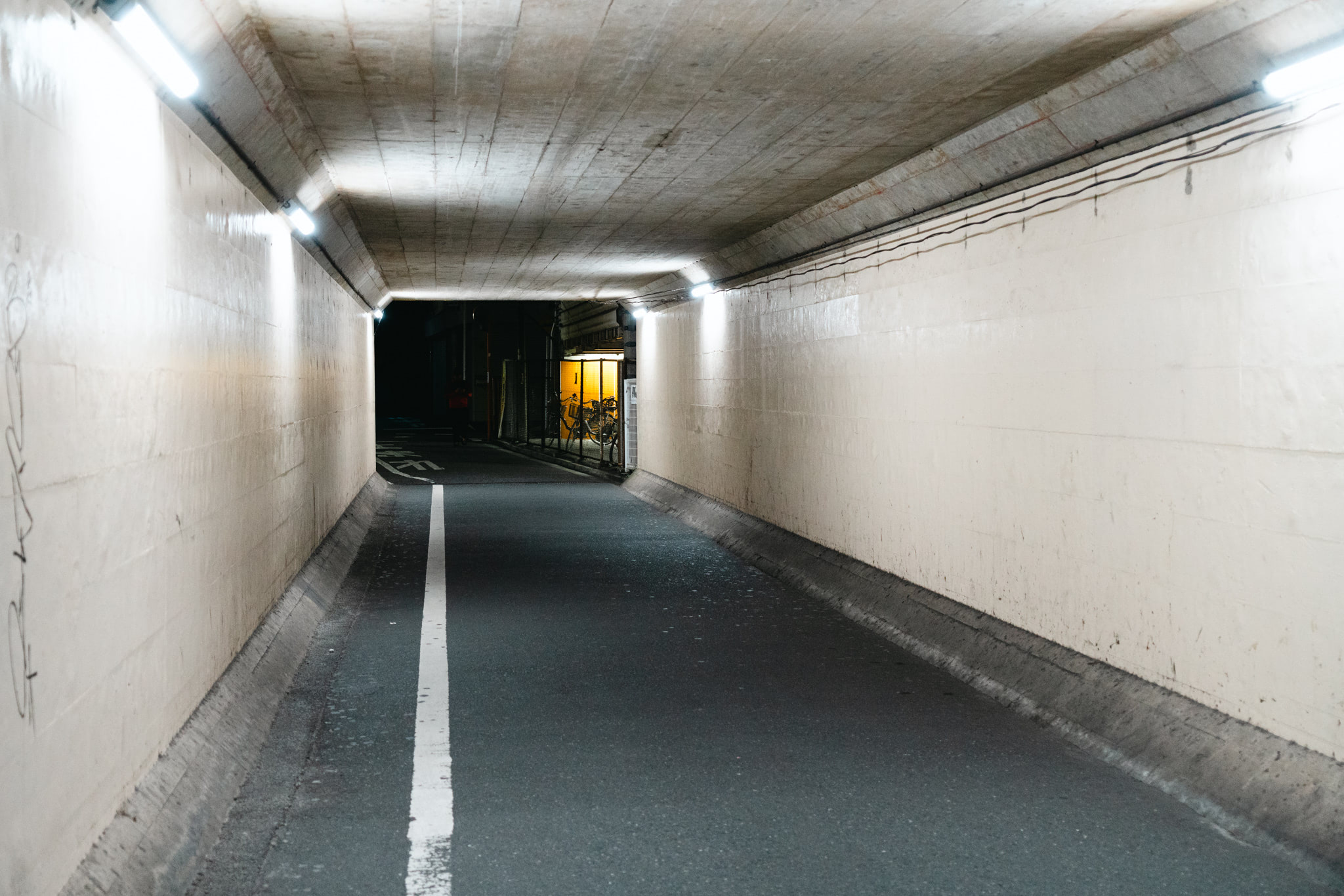 Nighttime view of a dimly lit pedestrian tunnel in Japan.