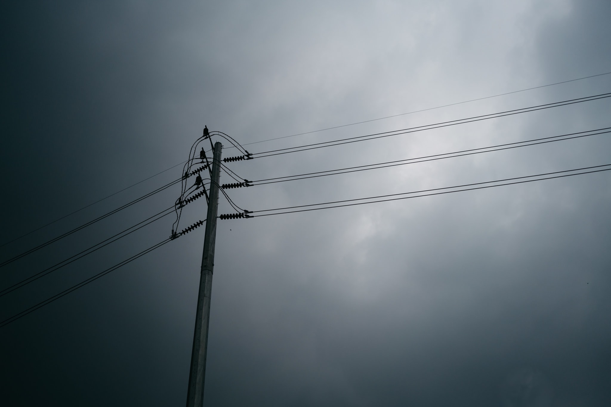 Utility pole with power lines against a stormy sky.