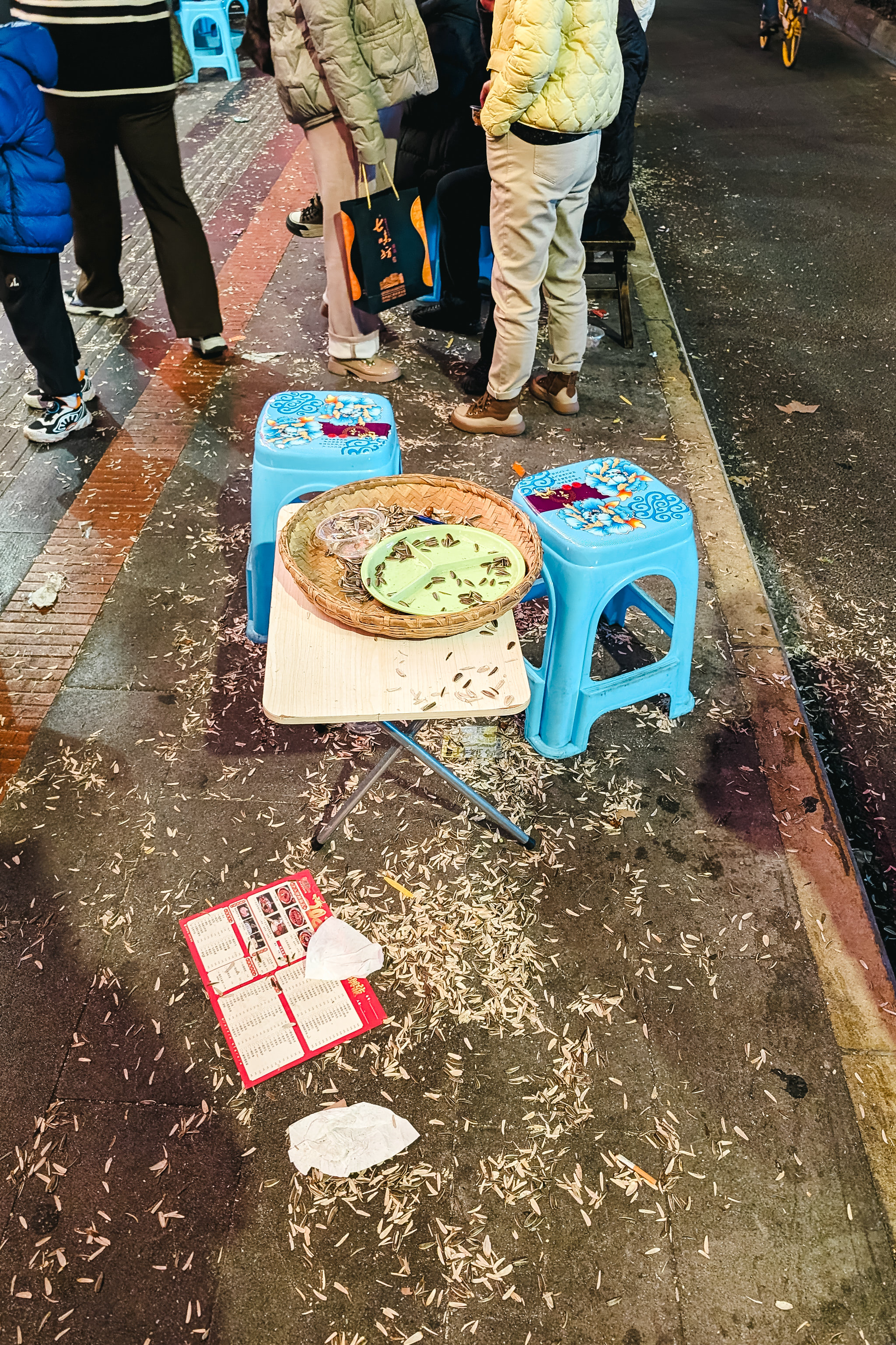 Sunflower seed shells scattered on the ground around small tables and stools in China.