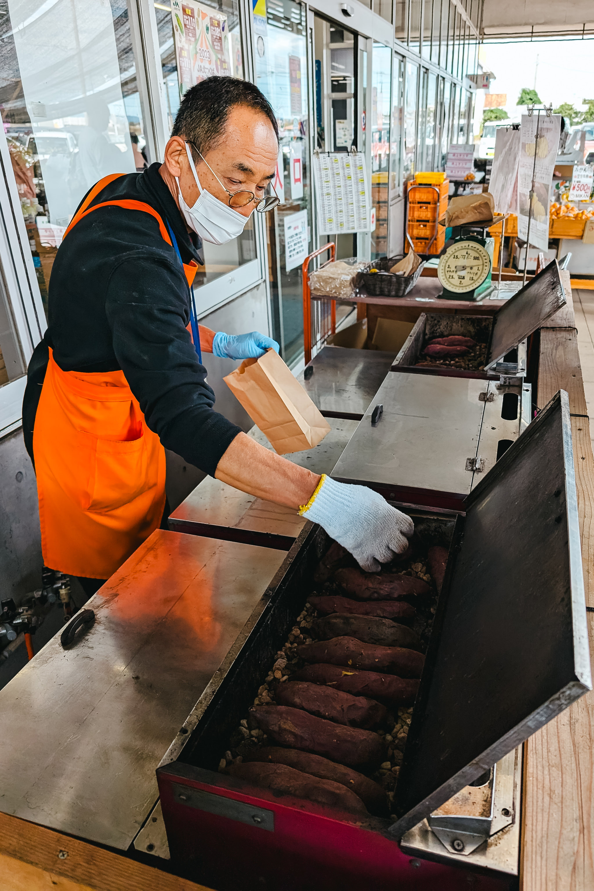 Person in mask bagging roasted sweet potatoes.