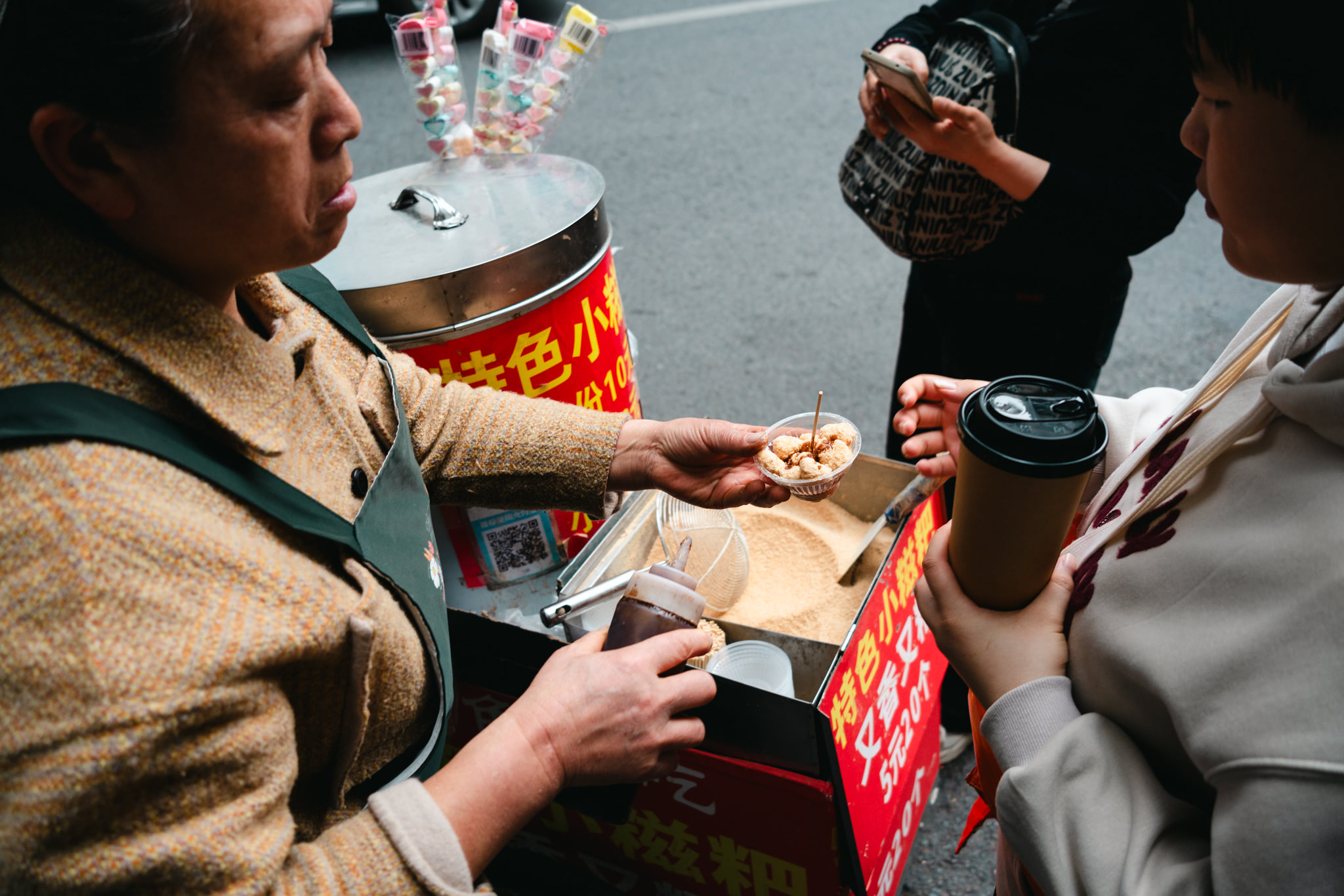 Street vendor handing a customer a small cup of street food.