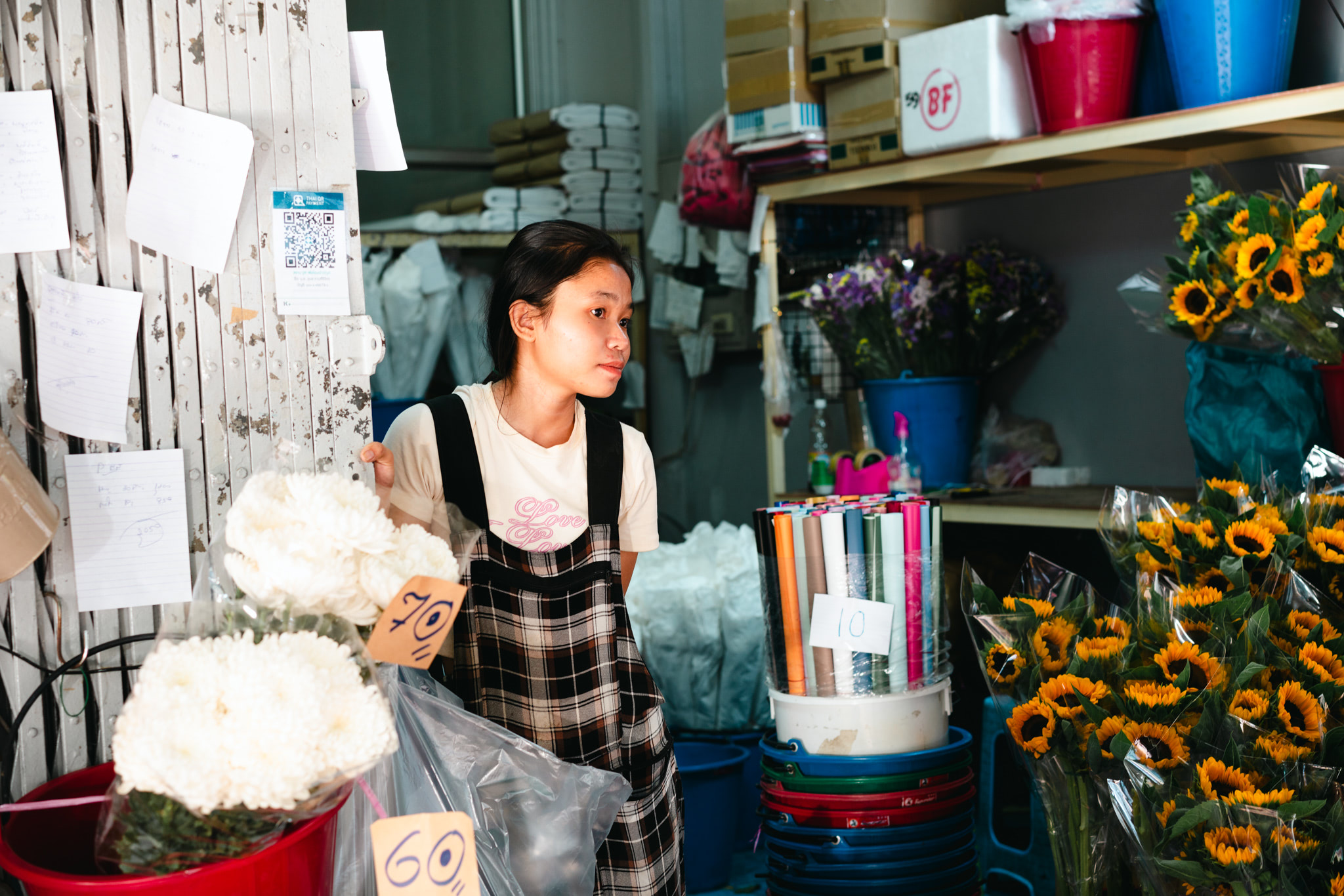 Young woman at a Bangkok flower market holding white flowers.