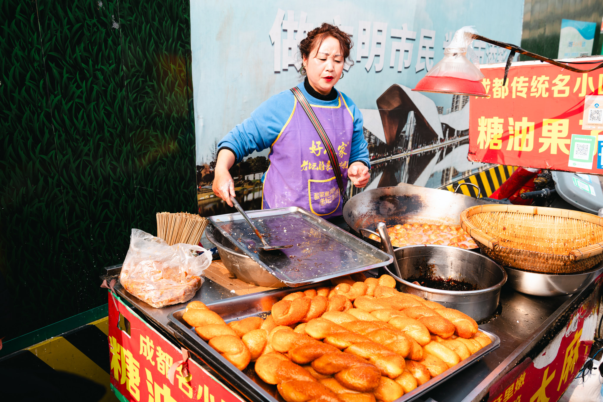 A woman selling fried bread at a Chengdu street food stall.
