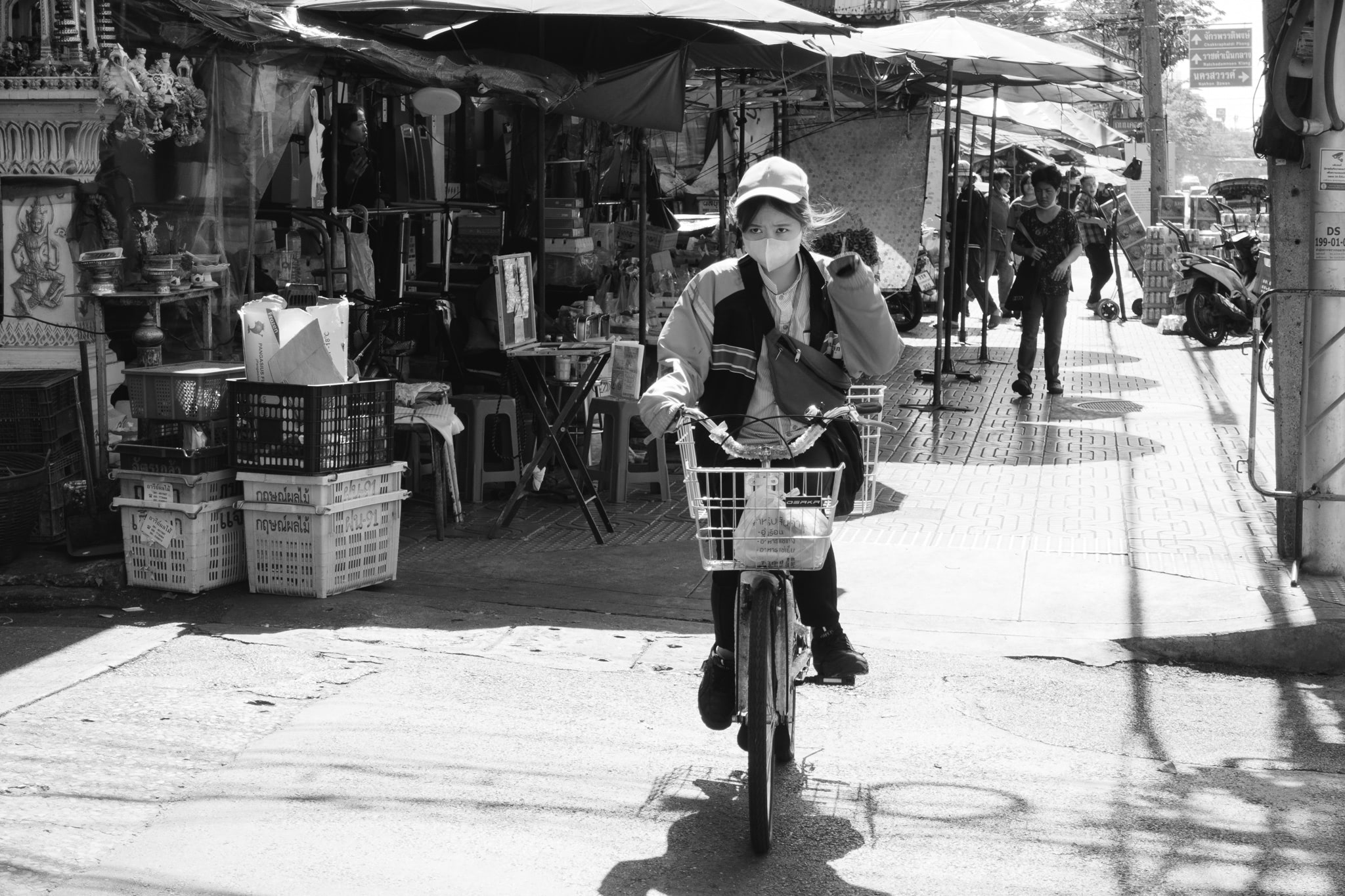 Woman wearing a face mask riding a bicycle in Bangkok.