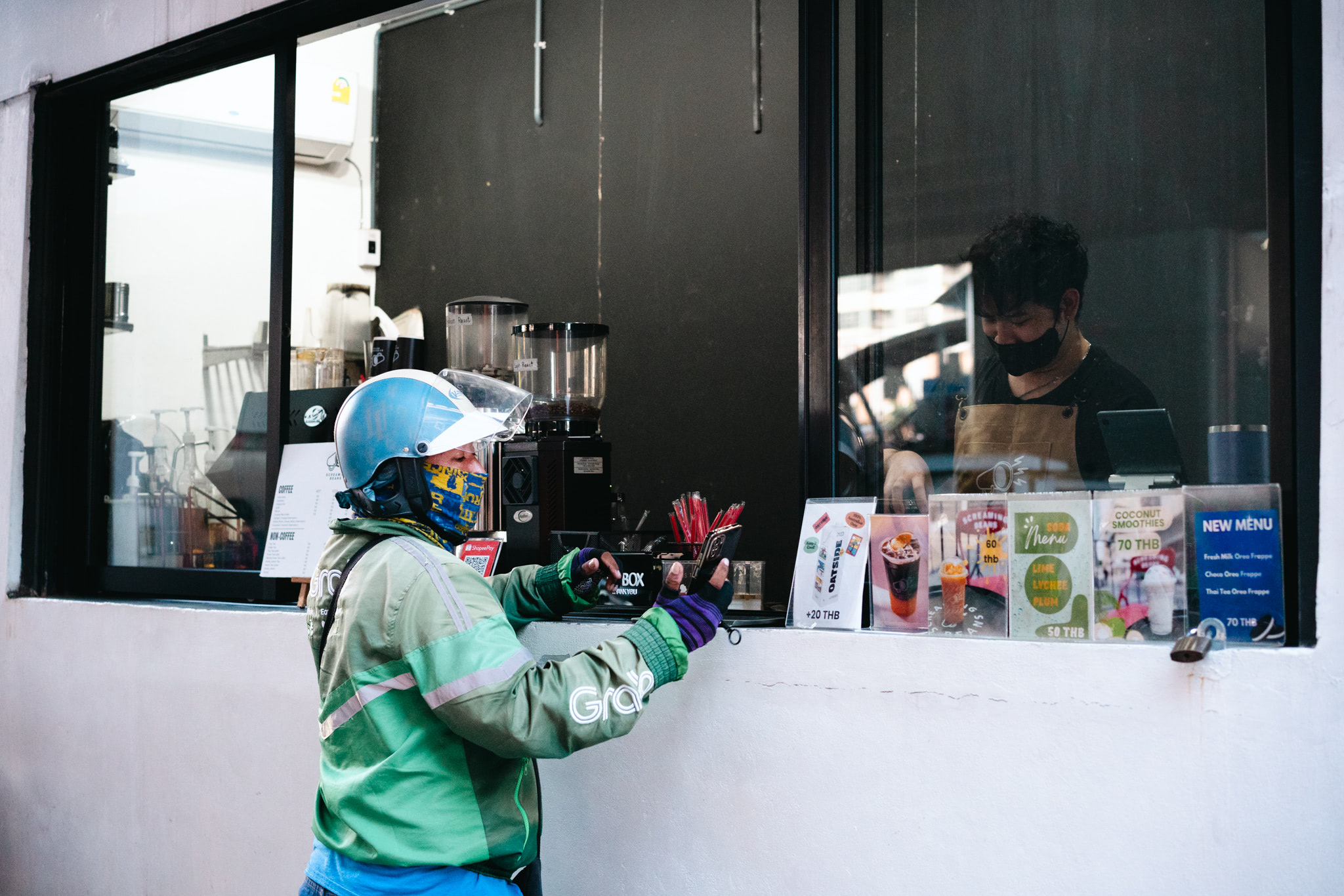 Grab delivery driver using a smartphone to order coffee at a shop.