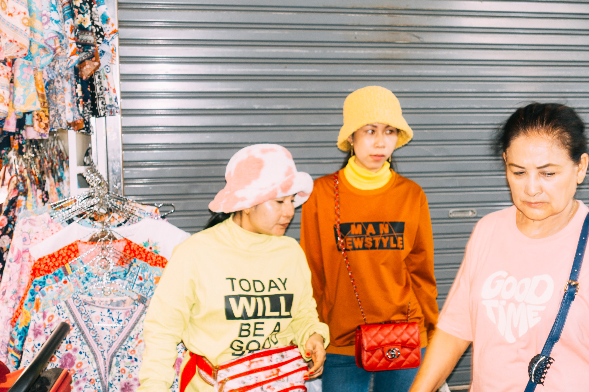 Three women in stylish clothing at a Bangkok market.