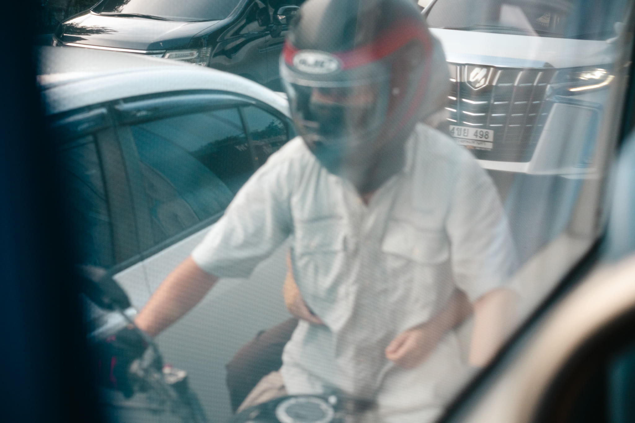 Person wearing a motorcycle helmet sitting on a motorbike in Bangkok traffic.