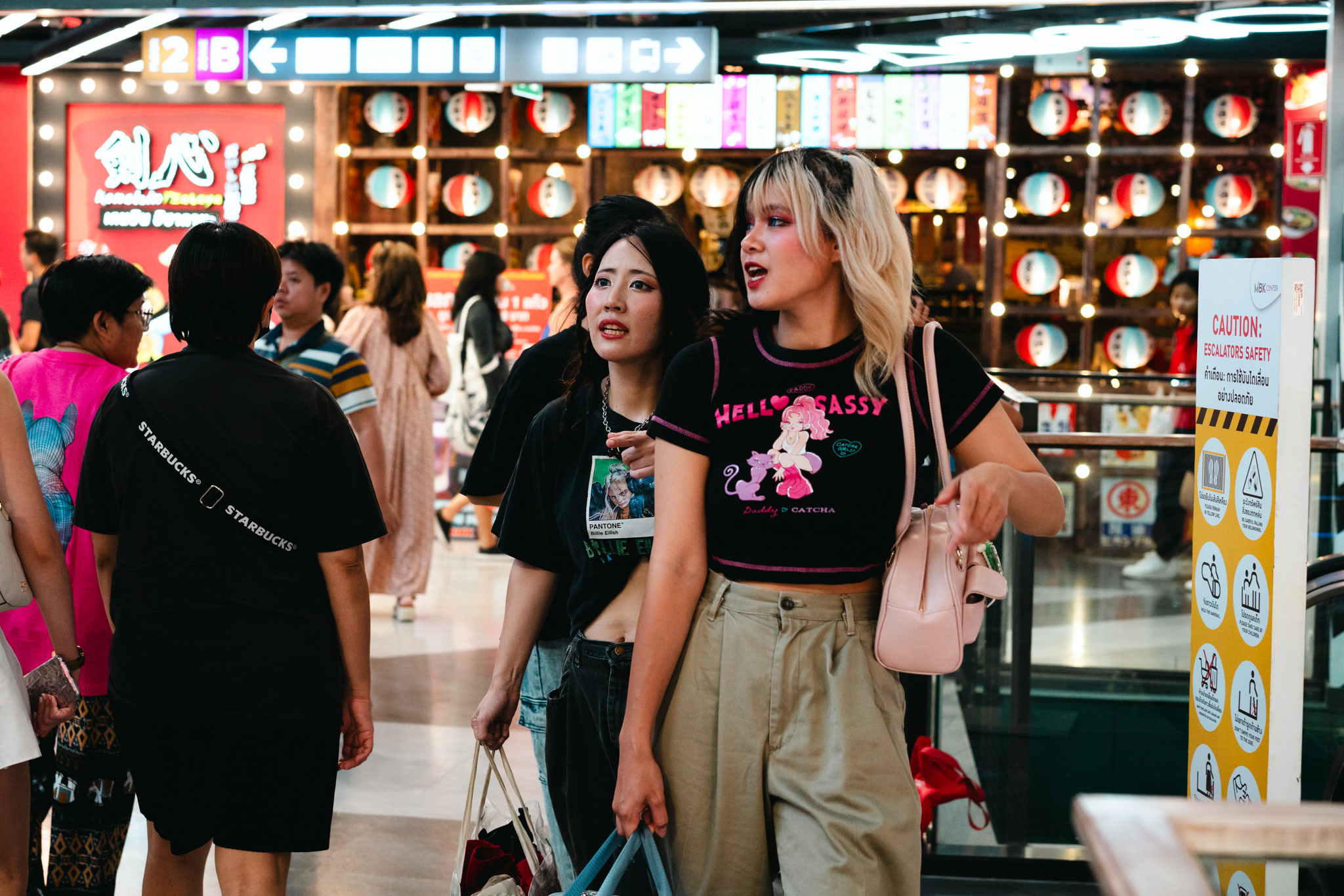 Two young women in stylish outfits shopping in a mall.