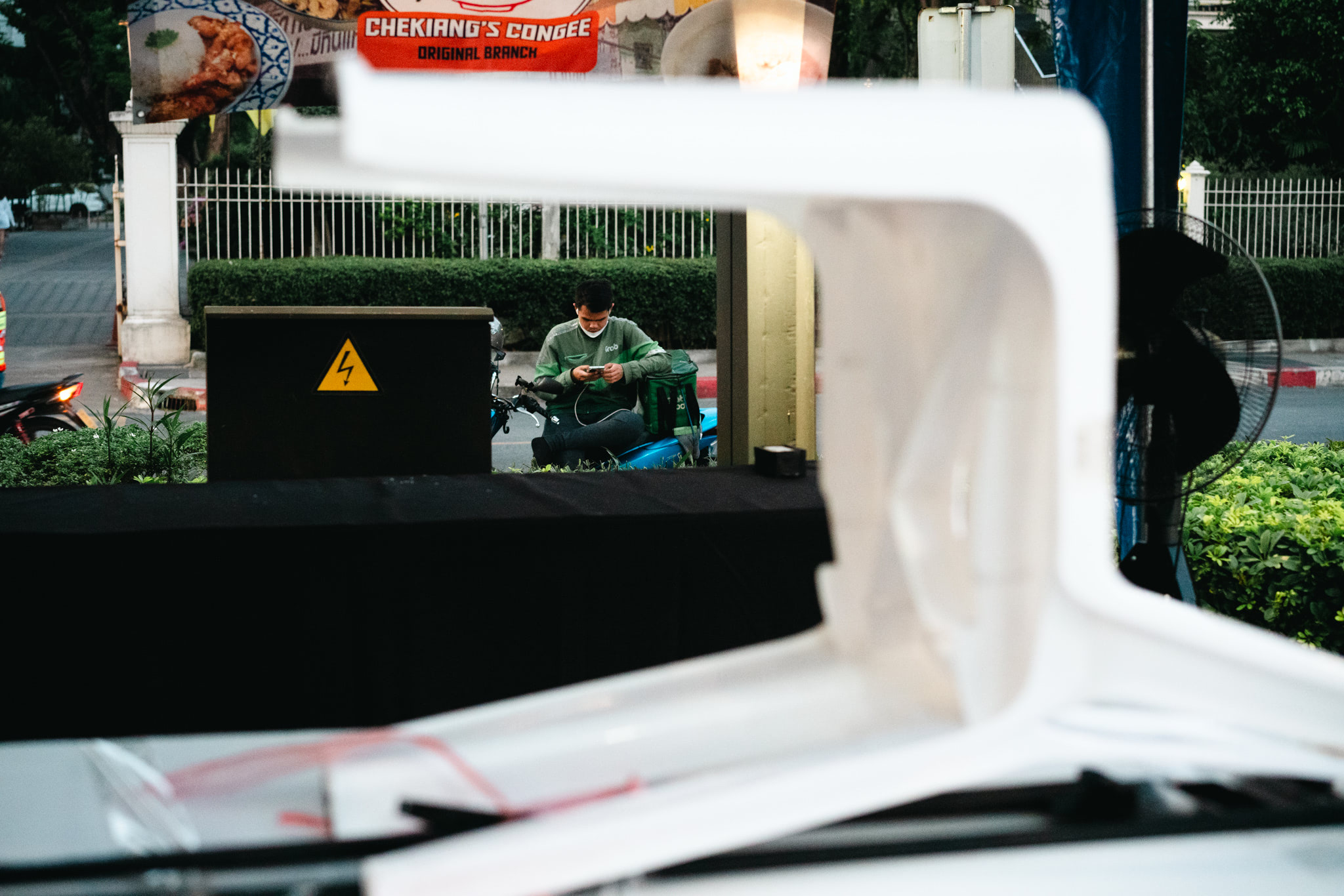 Person on phone, sitting on motorbike, seen through a white object.