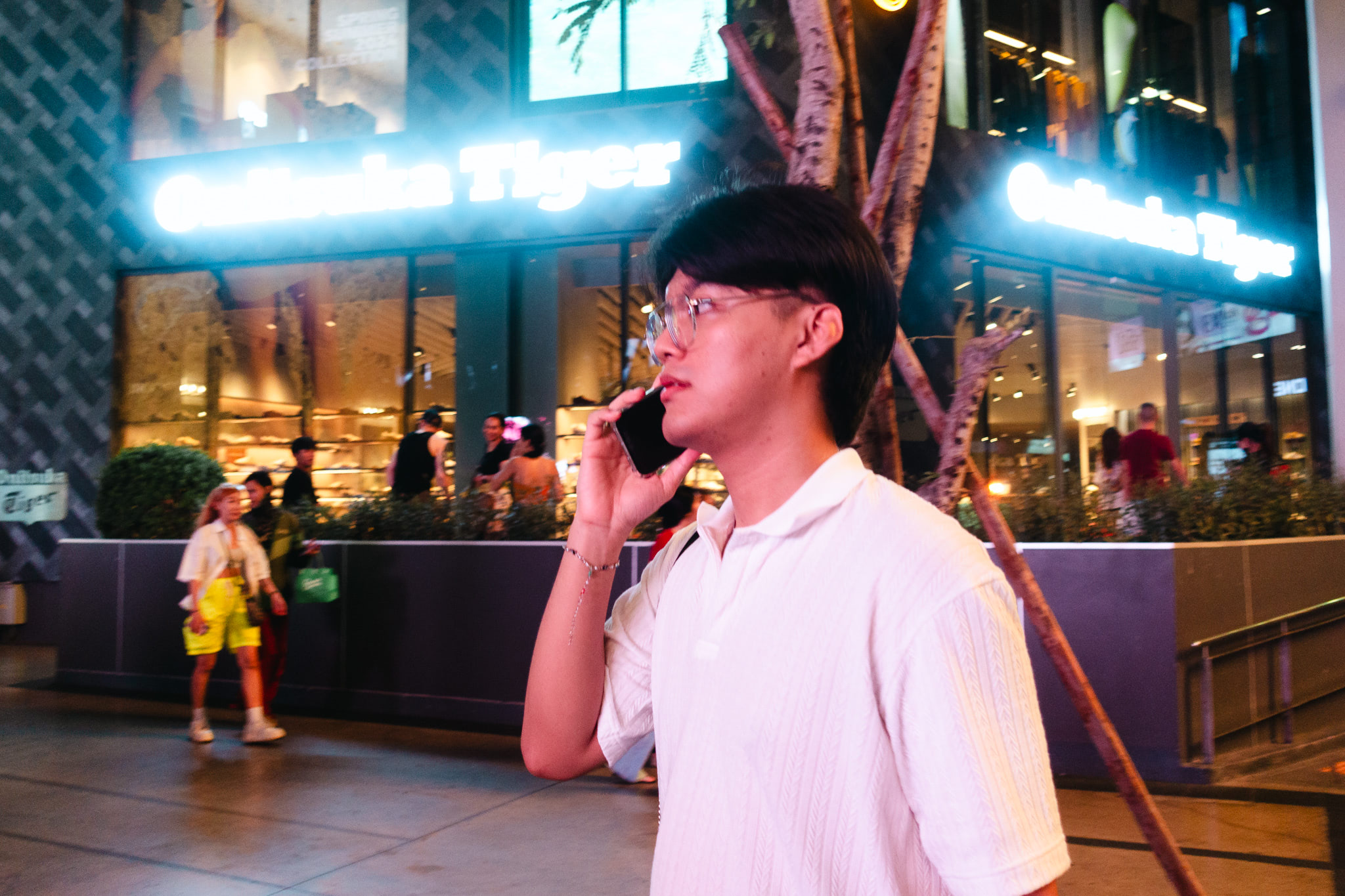 Man on phone in front of a California Tiger store at night.
