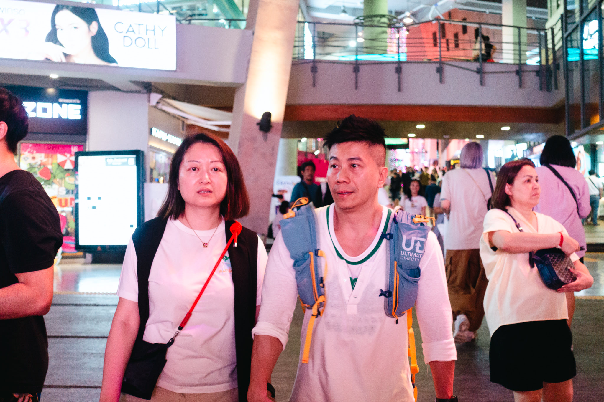 A man and woman walking in a crowded shopping mall.