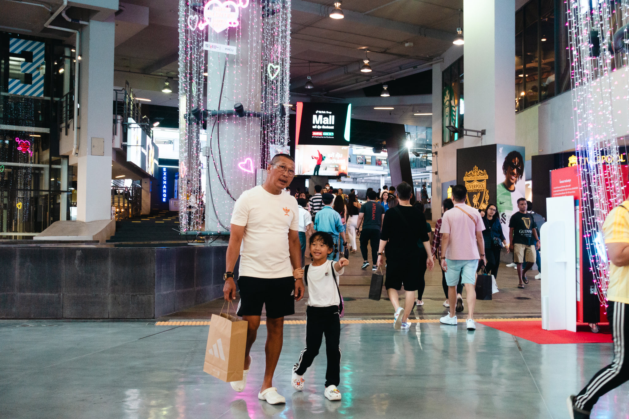 Man and child walking in a mall, holding hands.