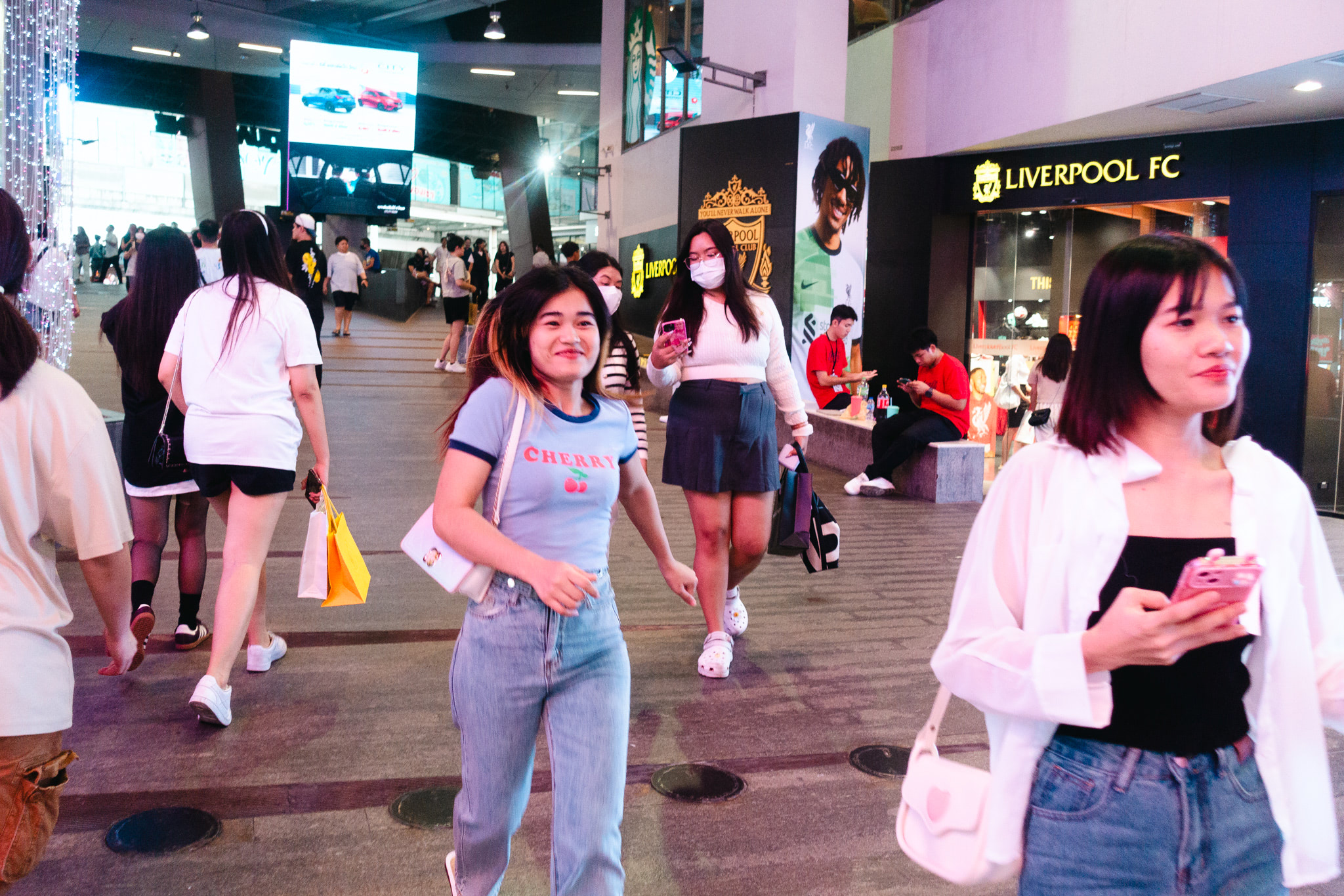 Young woman in jeans and a cherry shirt walking in a city mall.