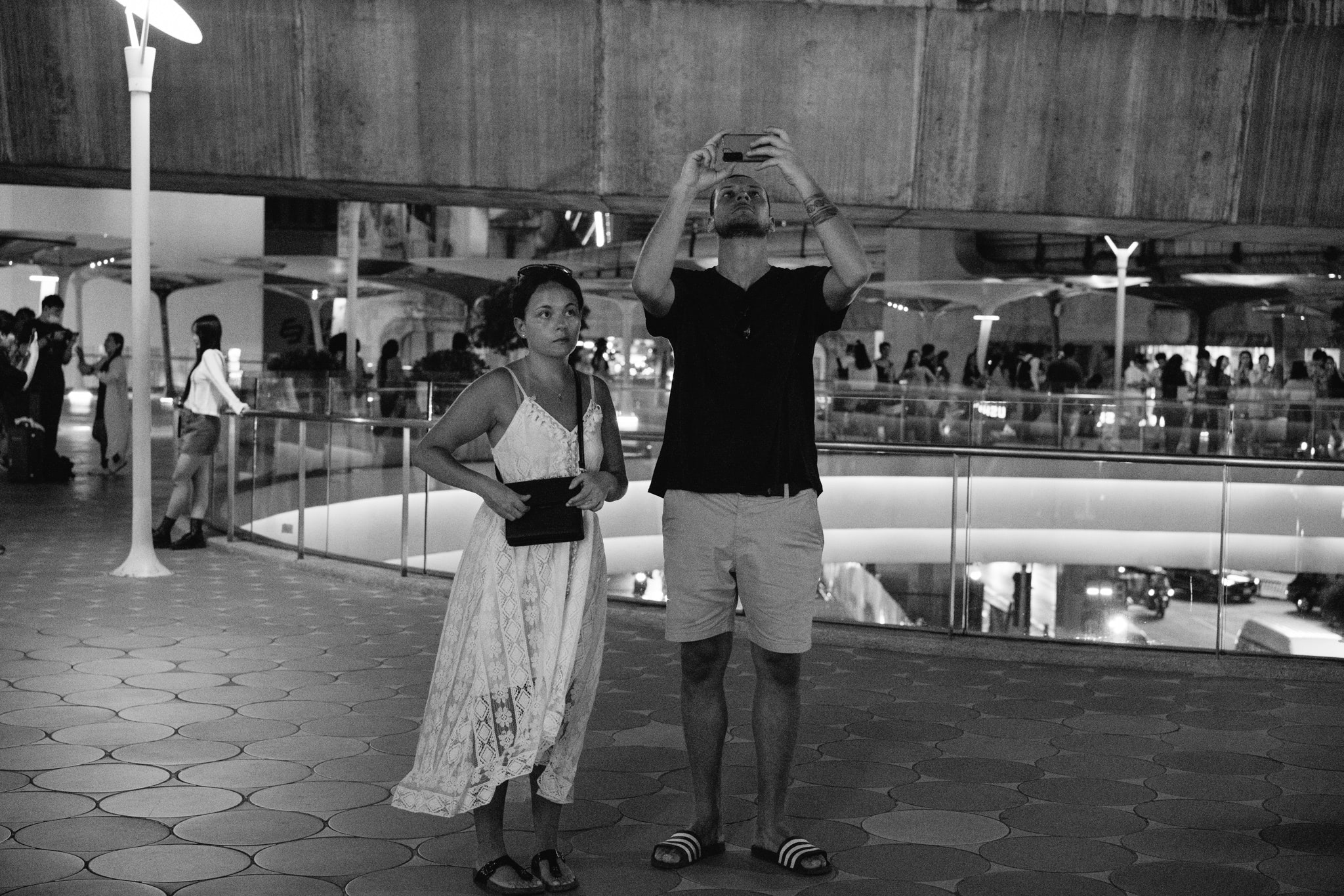 Black and white photo of a man and woman taking a photo in Bangkok.