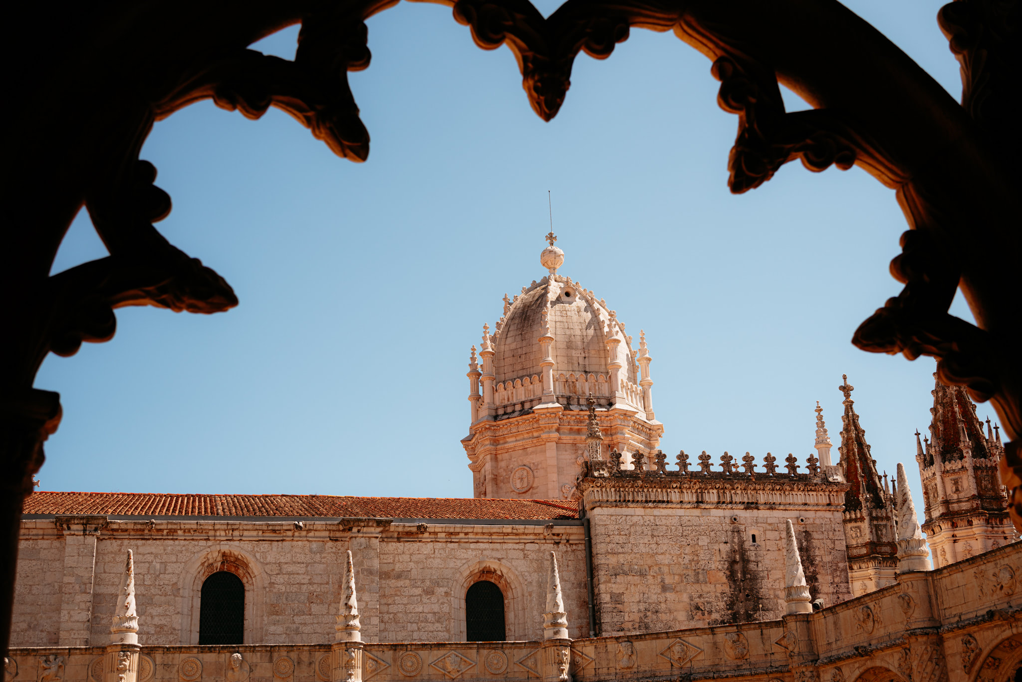 Jerónimos Monastery dome and cloister, viewed through ornate stone archway.