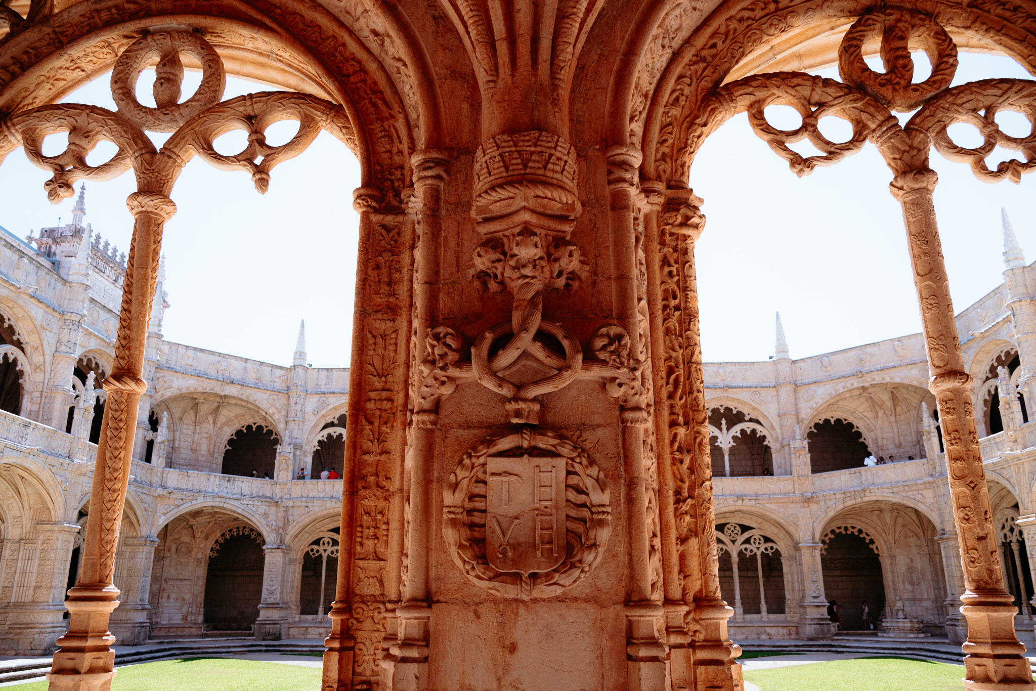 Intricate stone archway of Jerónimos Monastery cloister, showing a coat of arms.