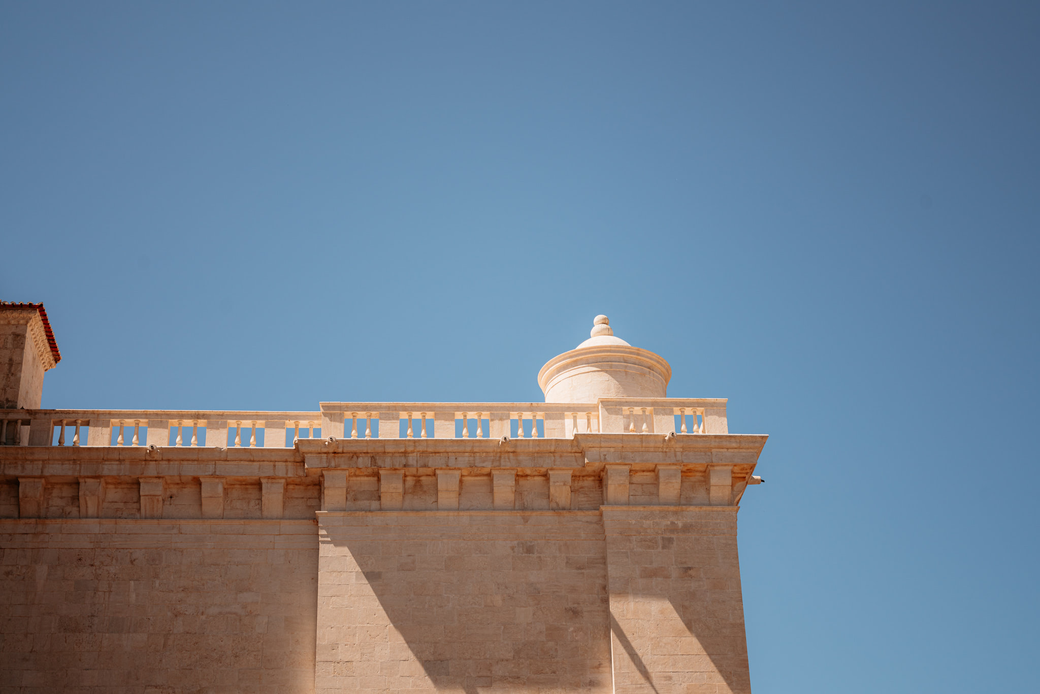 Jerónimos Monastery rooftop detail against a clear blue sky.