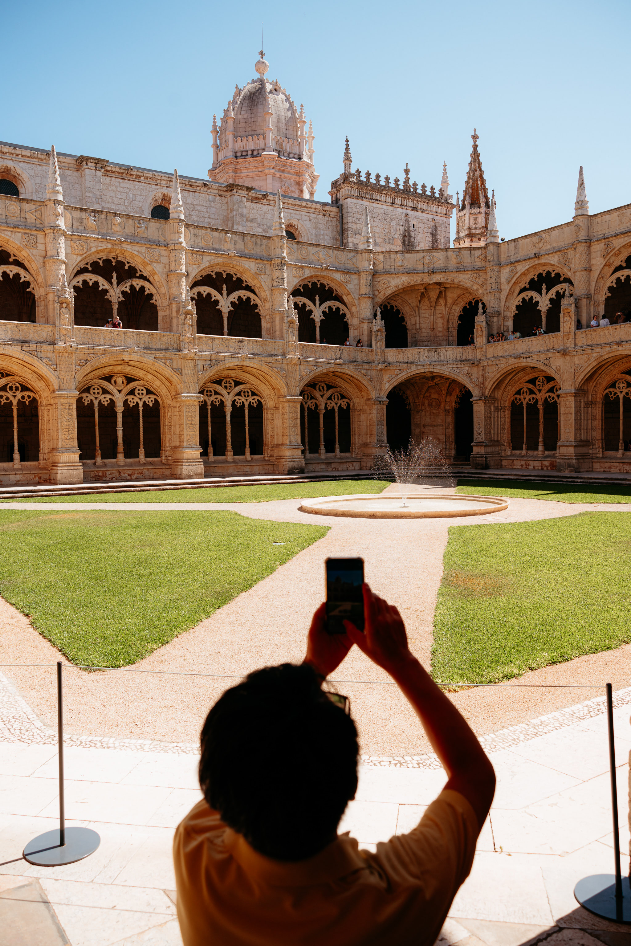 Person taking a picture of Jerónimos Monastery courtyard with a smartphone.