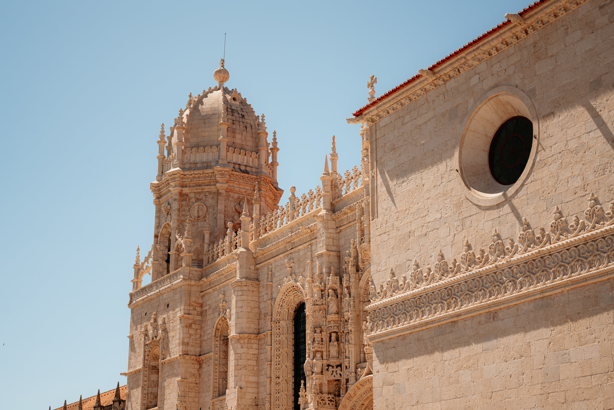 Jerónimos Monastery exterior detail, showing ornate stonework and a domed turret.
