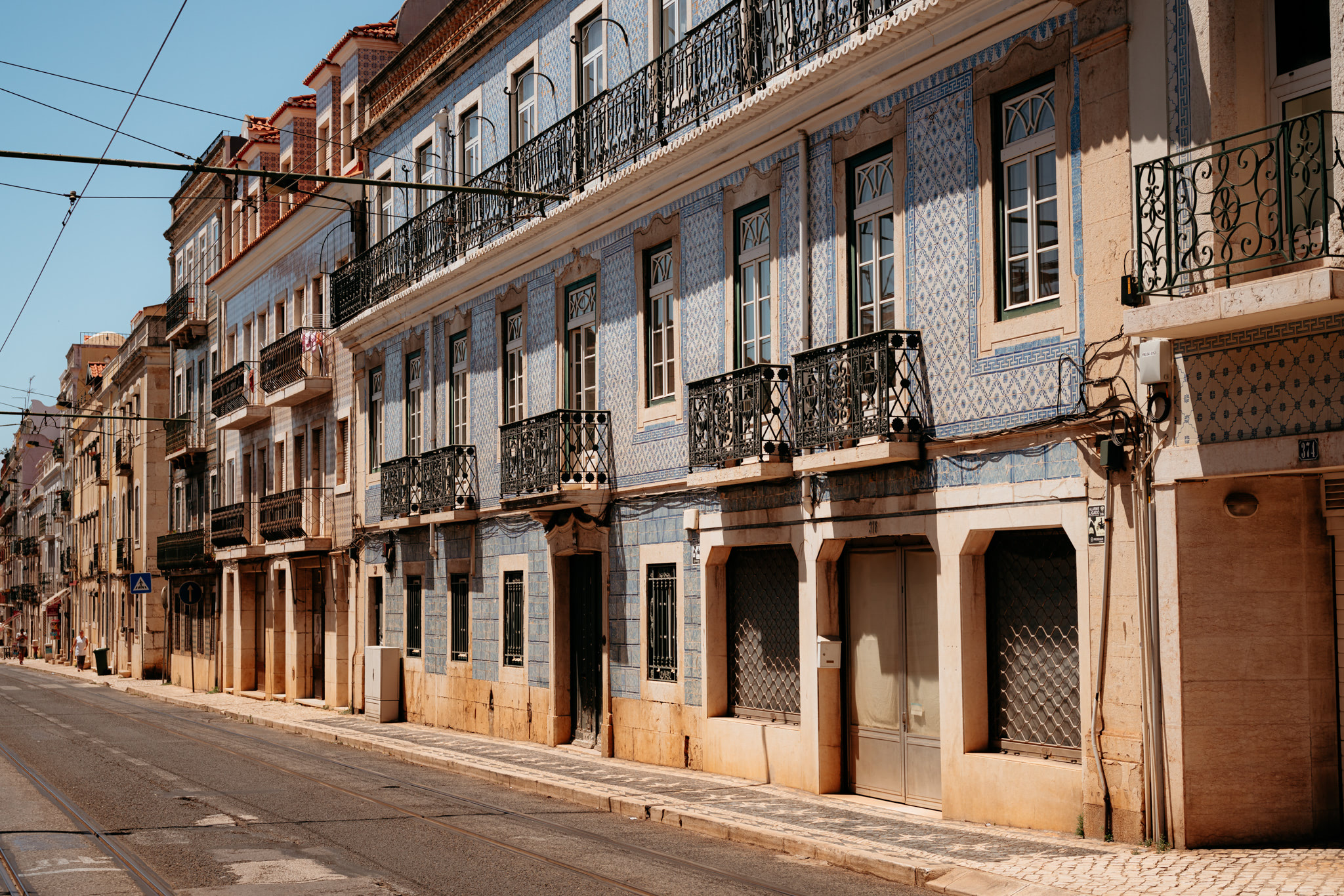 Lisbon street scene with blue and white tiled buildings and balconies.