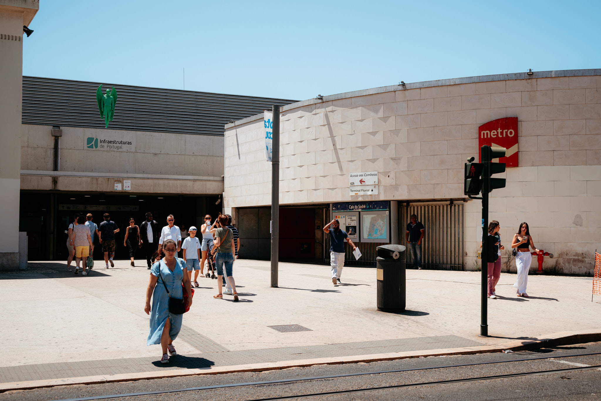 People walking outside a Lisbon metro station on a sunny day.
